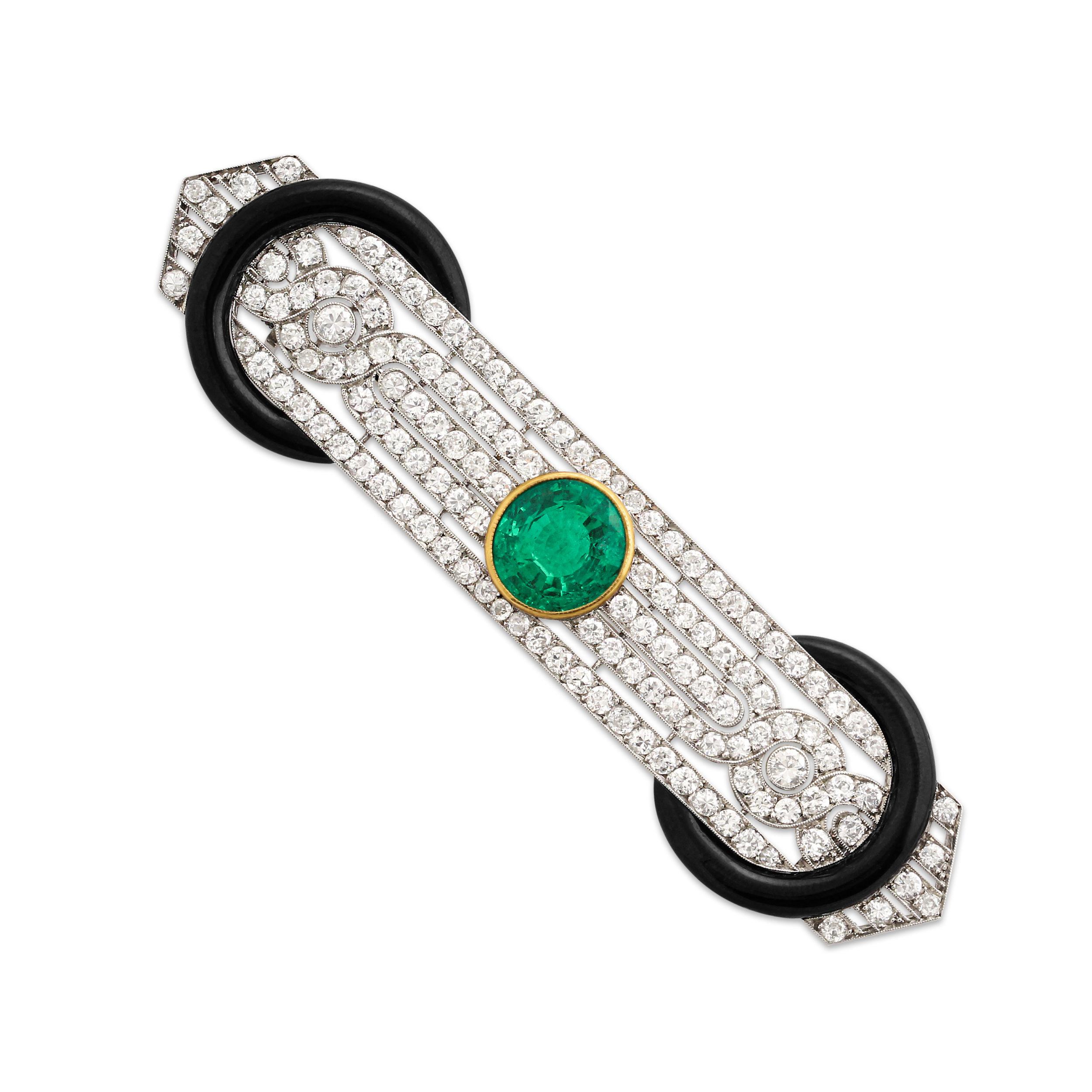 An Art Deco emerald, diamond and enamel brooch. The brooch is set at the centre with  2.70 carat Colombian emerald bezel set in yellow gold surrounded by approximately 5.50 carats of diamonds mounted in platinum with black enamel accents on either