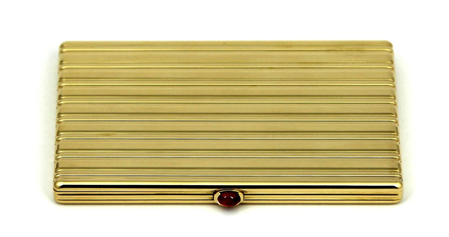 A rectangular 18 karat yellow gold cigarette case, by Cartier, dated 1947, with fitted presentation box. The exterior surface of the case is patterned with undulating horizontal stripes. The push-in ruby cabochon thumb-piece opens the case to reveal