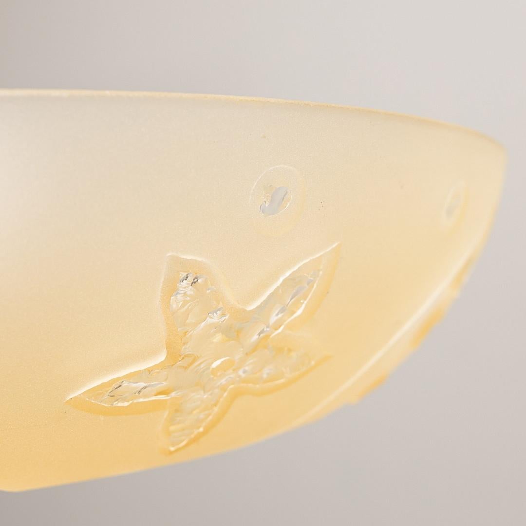 A 1940s Swedish Modern pendant with citrine glass and a brass stem and canopy. The glass with a frosted floral design. Circa 1940.