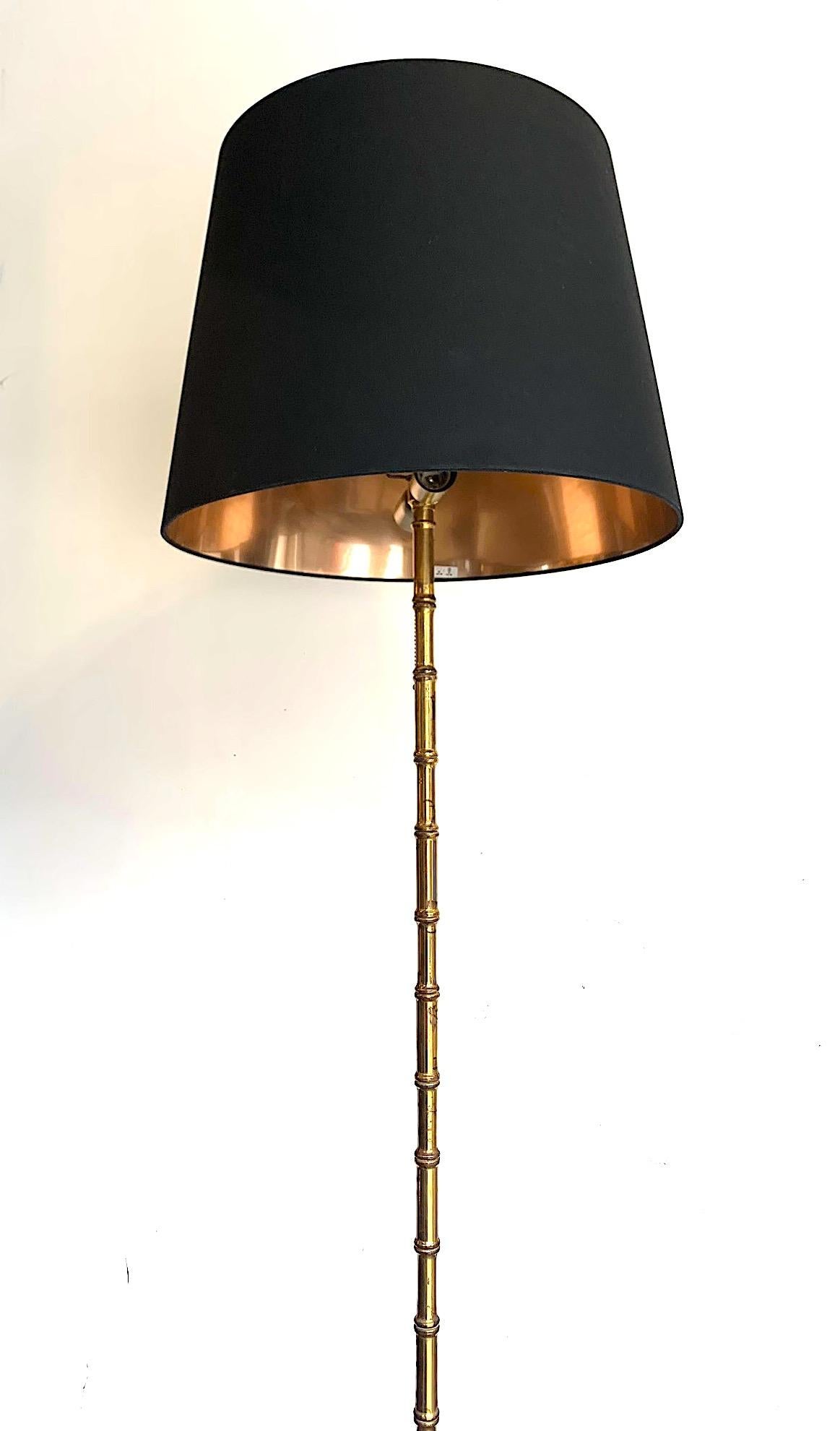 A 1950s brass Maison Baguès style faux bamboo floor lamp with tripod feet. With 2-light fittings and new bespoke black shade with gold linings. Re wired with new brass fittings and PAT tested.