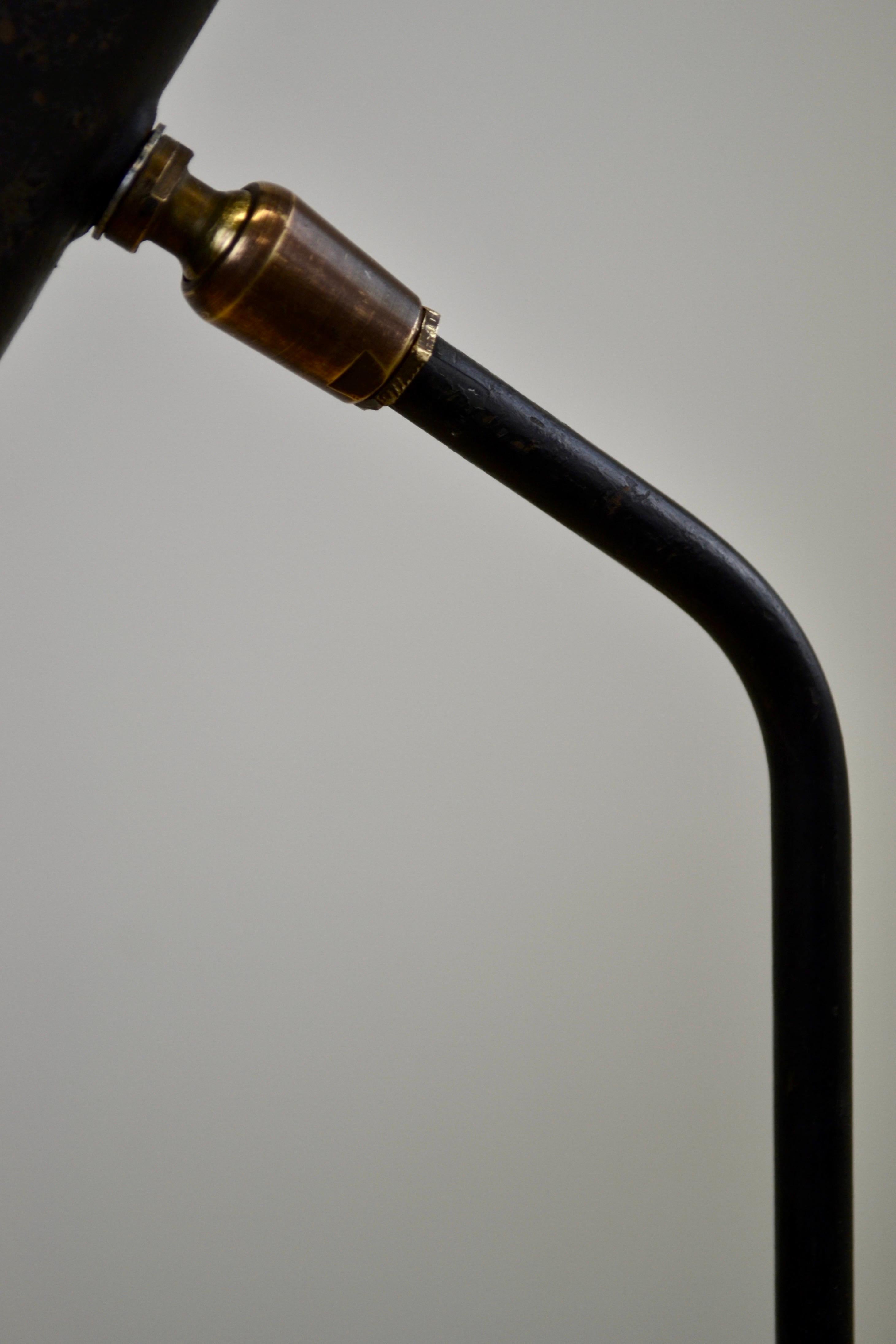 An elegant clip-on lamp from the 1950s by René-Jean Caillette. Its body, crafted from black lacquered steel tubing, and its brass swivel joint showcase a timeless and understated design, enhanced by its well-preserved original patina. Secured with a