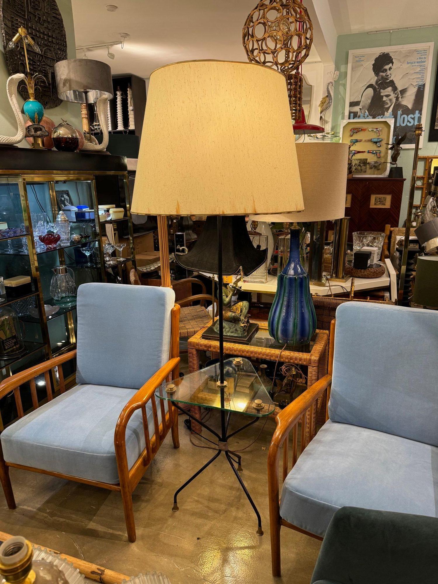 A 1950s French black lacquer tripod floor lamp with triangular glass centre table fixed with brass fixings, and centre detail.With orignal; large empire shade, which does have some slight staining but could be re-covered. Re wired with 2 new brass