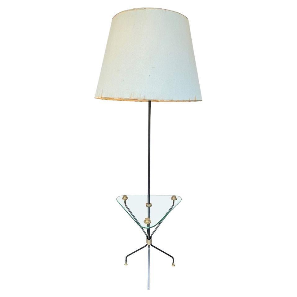 A 1950s French black lacquer and brass tripod floor lamp with glass table
