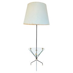 A 1950s French black lacquer and brass tripod floor lamp with glass table