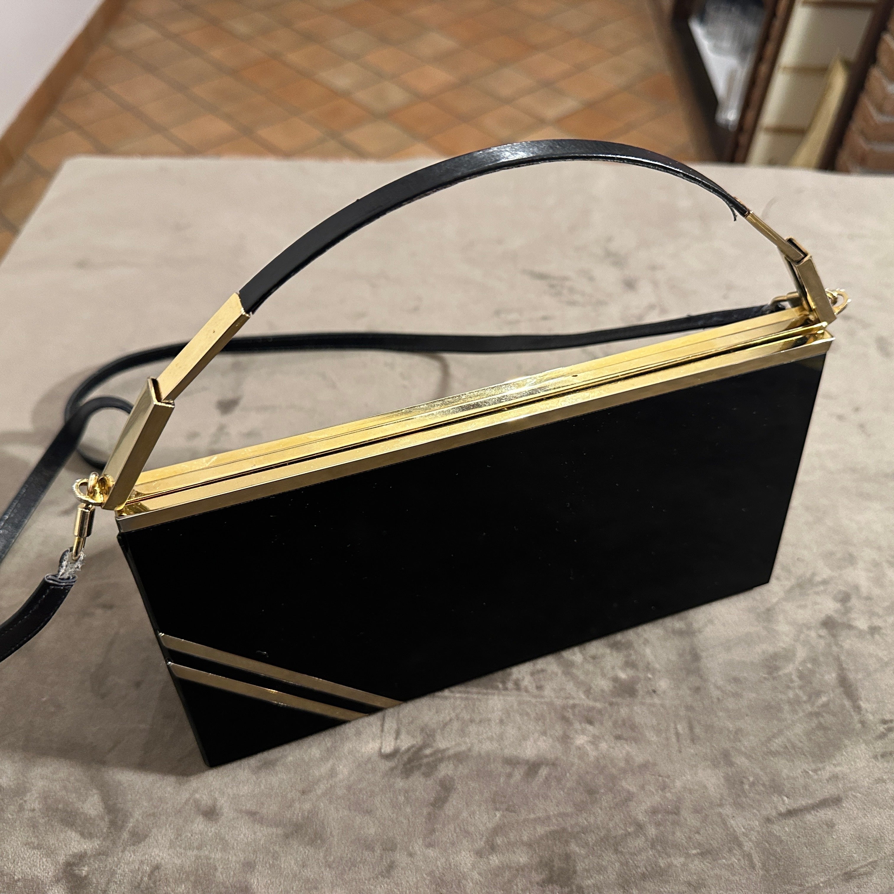 This 1950s Italian evening bag by Passanisi is a striking example of mid-century luxury and craftsmanship. Designed with high-quality black Lucite and brass, it exudes sophistication and timeless elegance. Made from glossy black Lucite, a durable