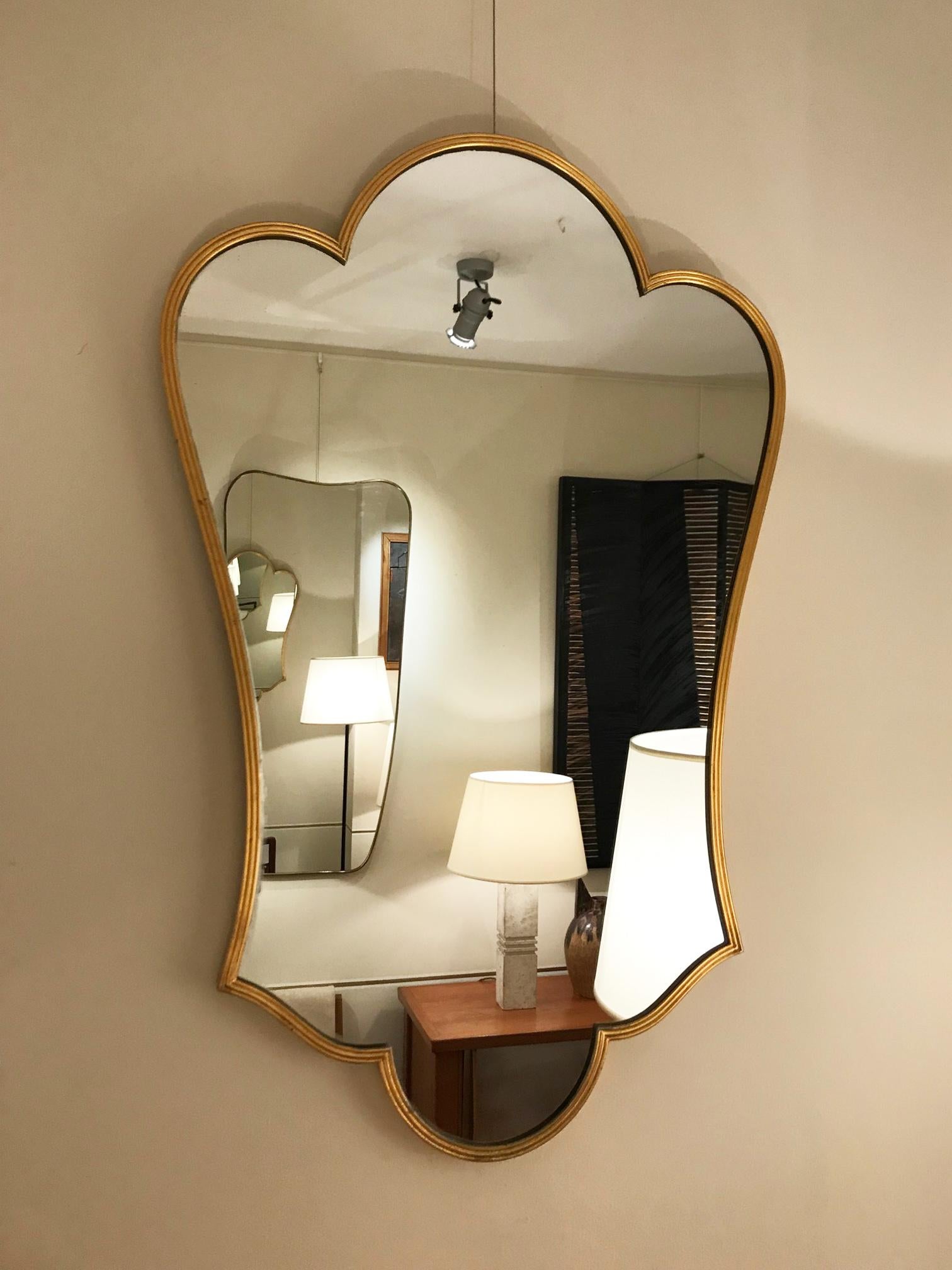 A gold lacquered brass shield shaped mirror
Italy, circa 1955.