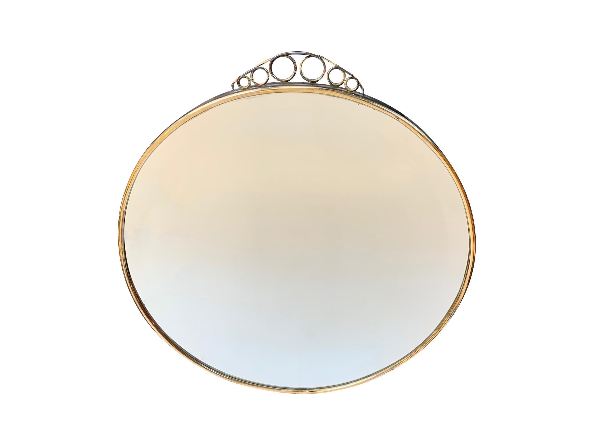 A 1950s Italian circular mirror with beveled glass with a brass frame and top scrolling detail.
