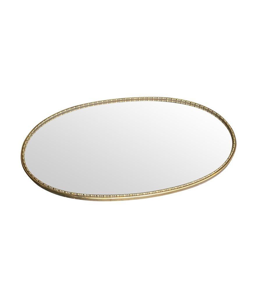 Ein ovaler, messinggerahmter Spiegel aus den 1950er Jahren mit Perlenrand und Massivholzrücken.