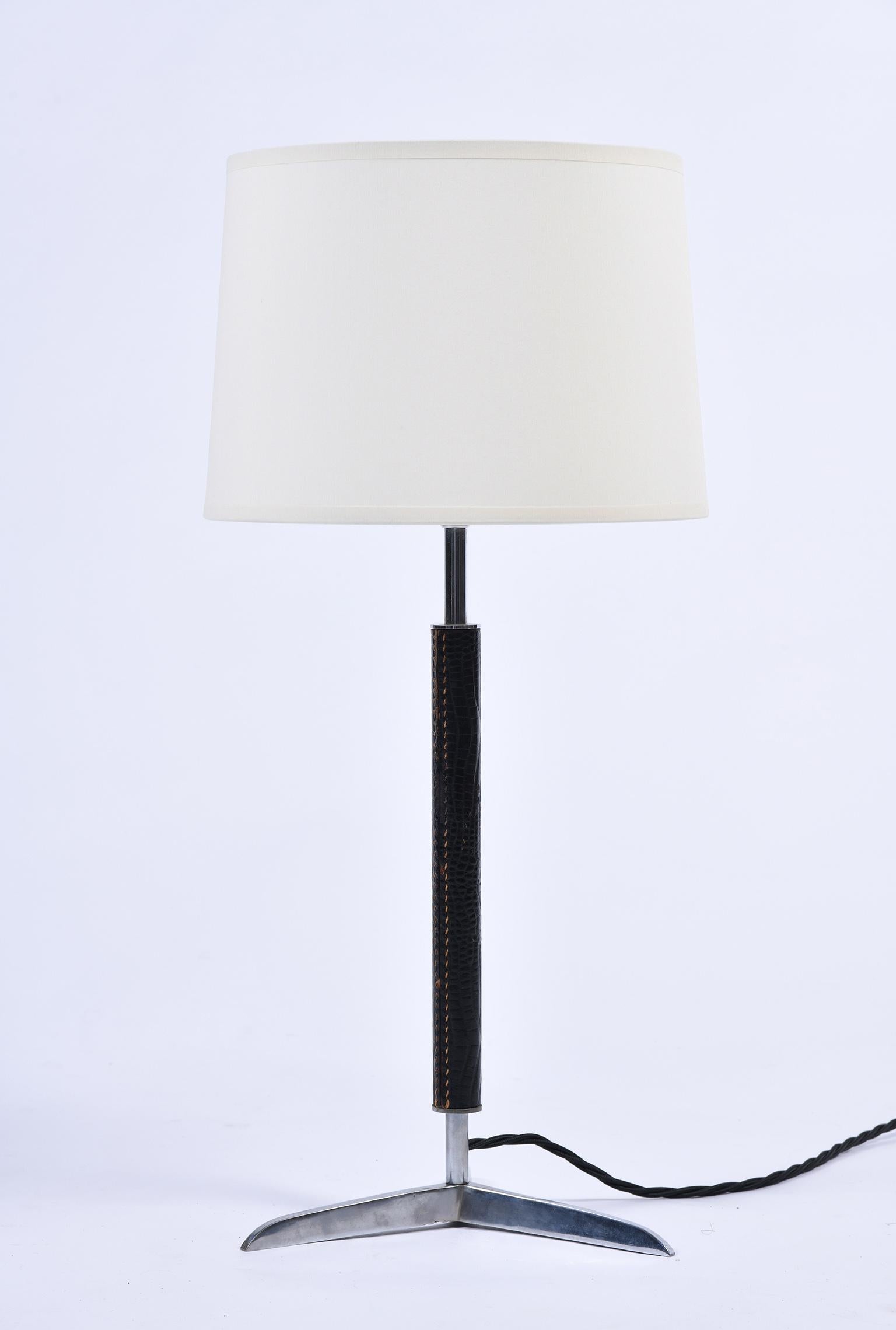 A stitched black leather and nickel-plated brass tripod table lamp
France, circa 1955.