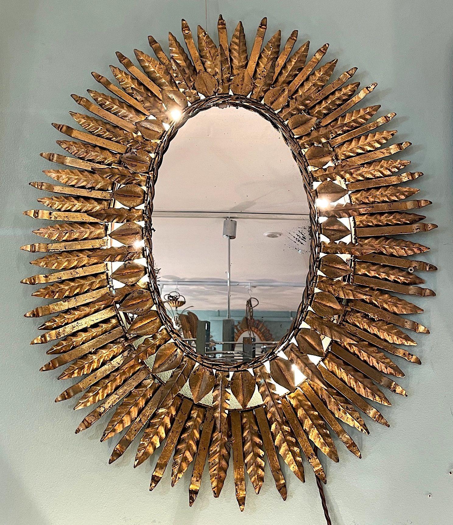 A 1950s Spanish oval wrought iron back lit sunburst mirror, with four lights behind the mirror. Re wired with new brass fittings and PAT tested.