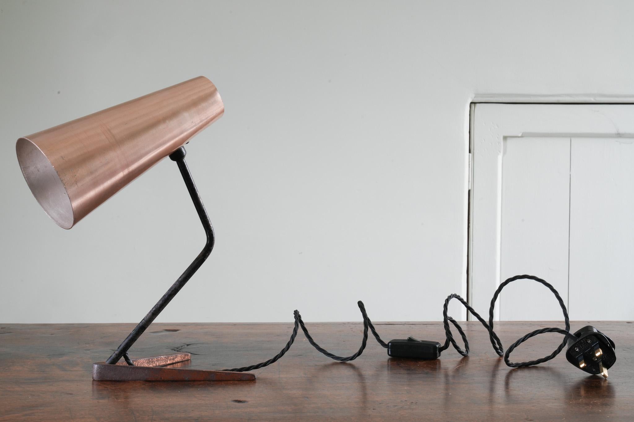 Copper anodised aluminium shade with a painted steel pivoting support resting on a copper plated V shaped brass base.
