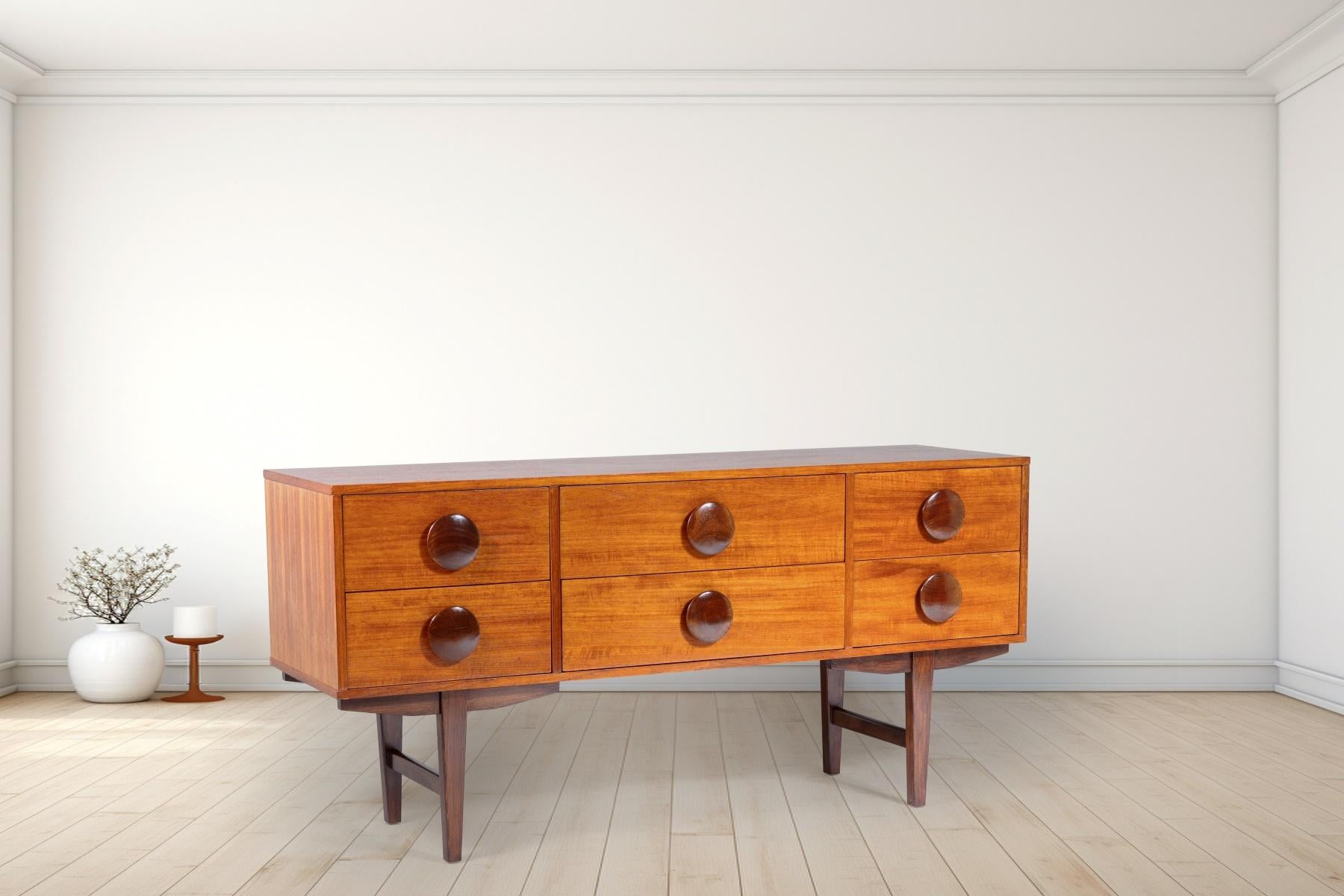 A small but stylish 1960s mid century sideboard, has a great look with central pair of wide drawers flanked by narrower drawers, drawer fronts feature large solid teak wood button handles in a contrasting tone which really gives the piece its