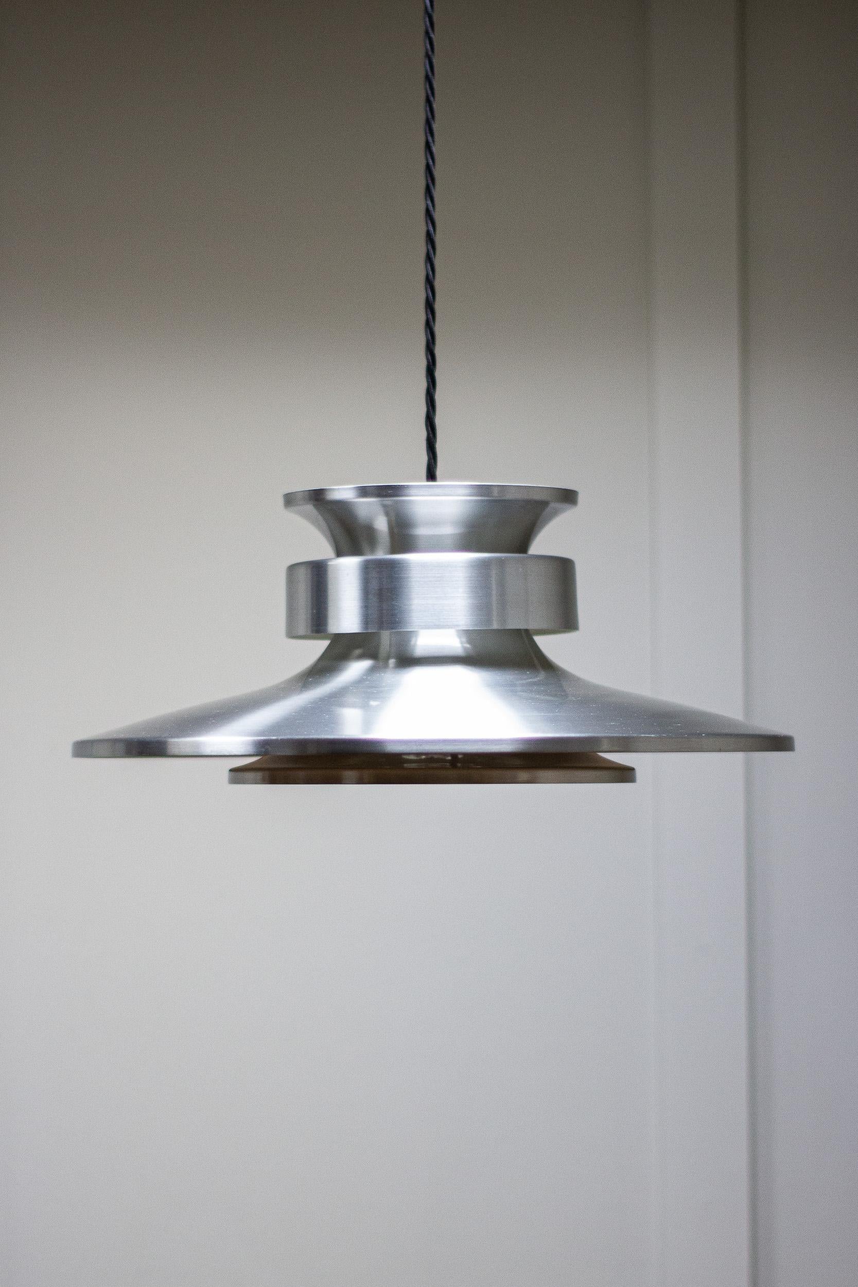 A 1960s midcentury pendant light made from pressed aluminium.

Fully rewired and new bulb holder. 

Possibly Danish.

Measures: Height 17cm
Width 42cm
Depth 42cm.
 