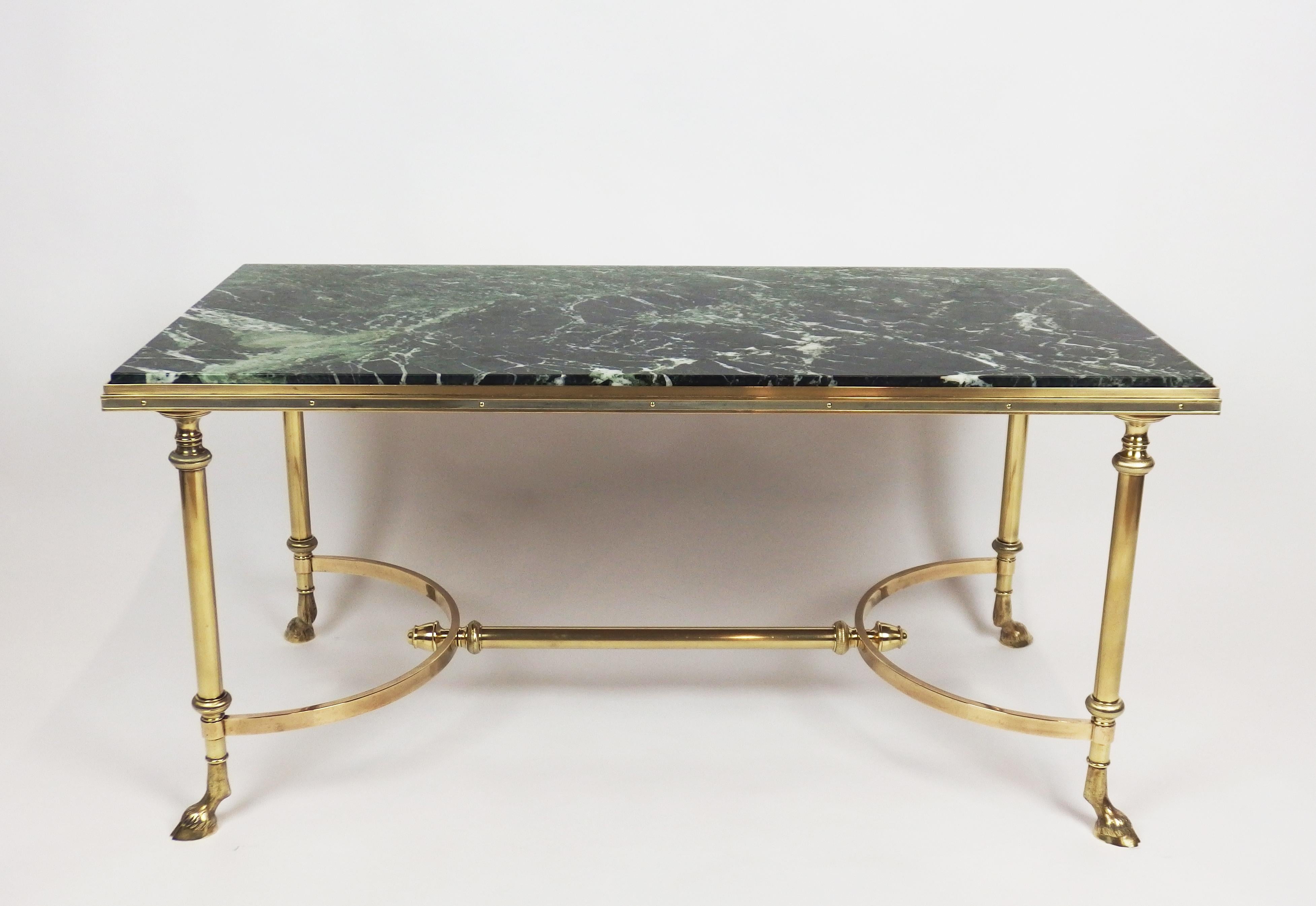 A refined coffee table inspired by neoclassical style with a green and variegated marble top in a brass frame with brass legs ending with bronze sabots in shape of animal feet.