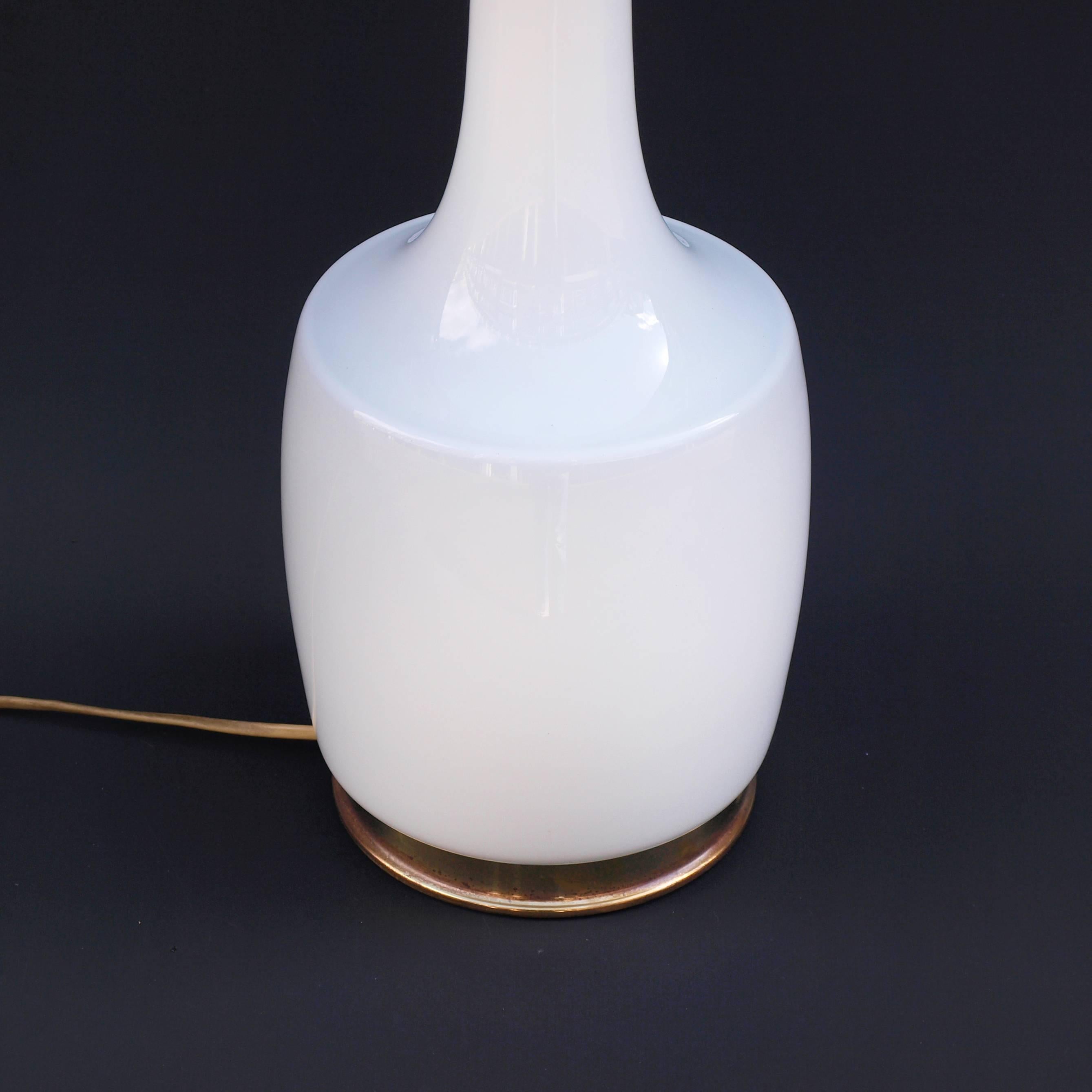 Une lampe en verre opalin blanc des années 1960 conçue par Holm Sorensen. Un design exceptionnel par la simplicité de sa forme, de sa fonction et de son matériau, avec une finition en laiton à la base et au col. Le minimalisme scandinave dans ce