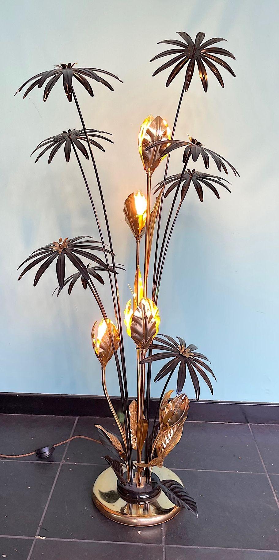 A 1970s French flower floor lamp in the style of Hans Kögl with five brass flowers each with lights in, surrounded by black enamel flowers on brass stems. Re wired with new brass fittings, antique gold cord flex and foot switch.