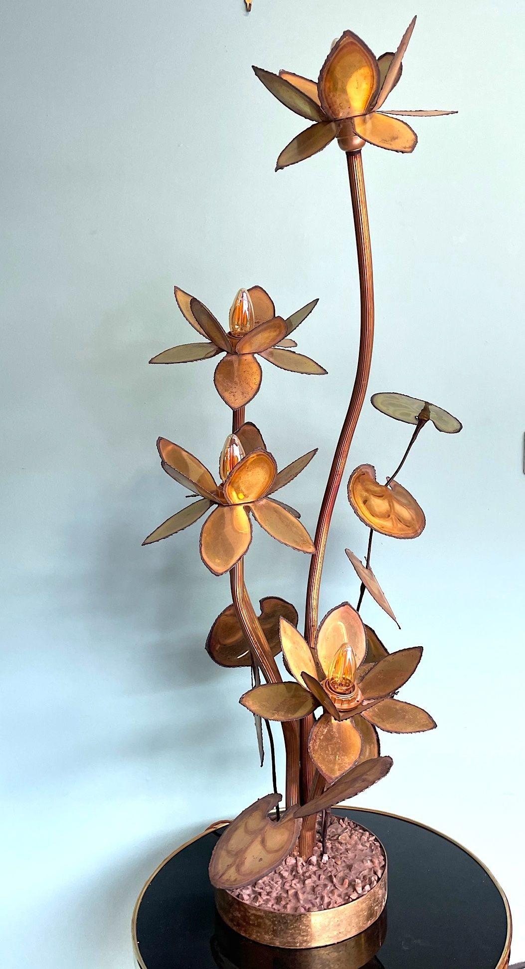 A 1970s French brass flower floor lamp in the style of Maison Jansen, with four torch cut brass flowers each with a single light fitting. Mounted on a a circular base with pebbles set in acrylic. Re wired with antique cord flex, new fittings, foot