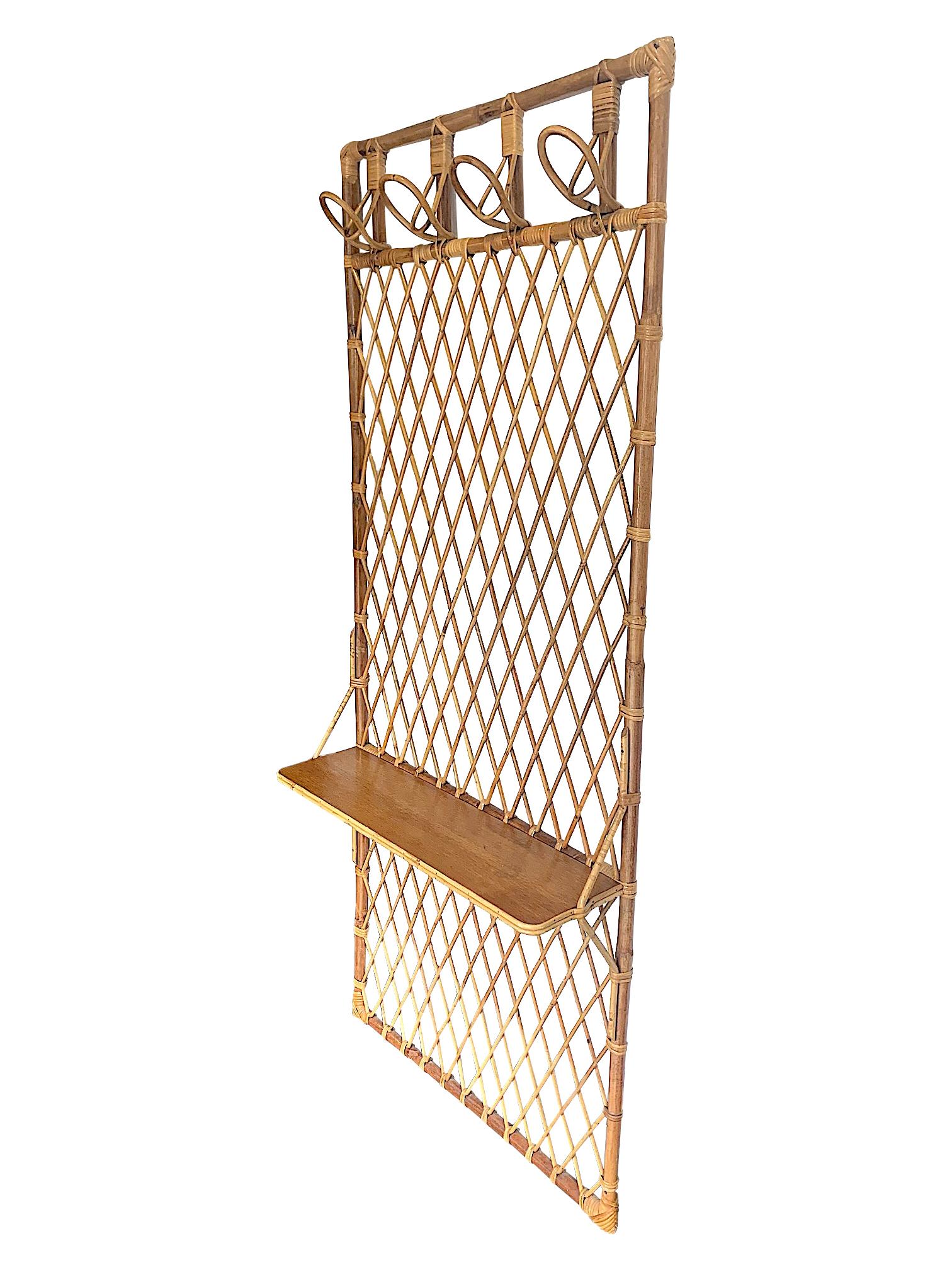 A 1970s French Riviera rattan and bamboo coat rack with four coat hooks, wooden shelf and geometric woven rattan back.
