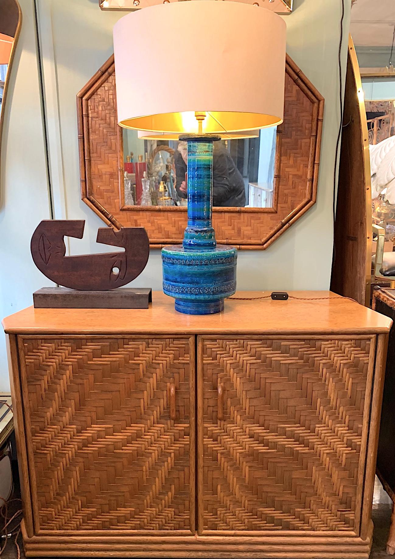 A 1970s French Riviera two door bamboo and rattan side cabinet with intricate woven detail on the doors. The door open to reveal 3 shelves and the sides have interesting angled detail so the width goes from 121cm wide at the front to 106cm wide at