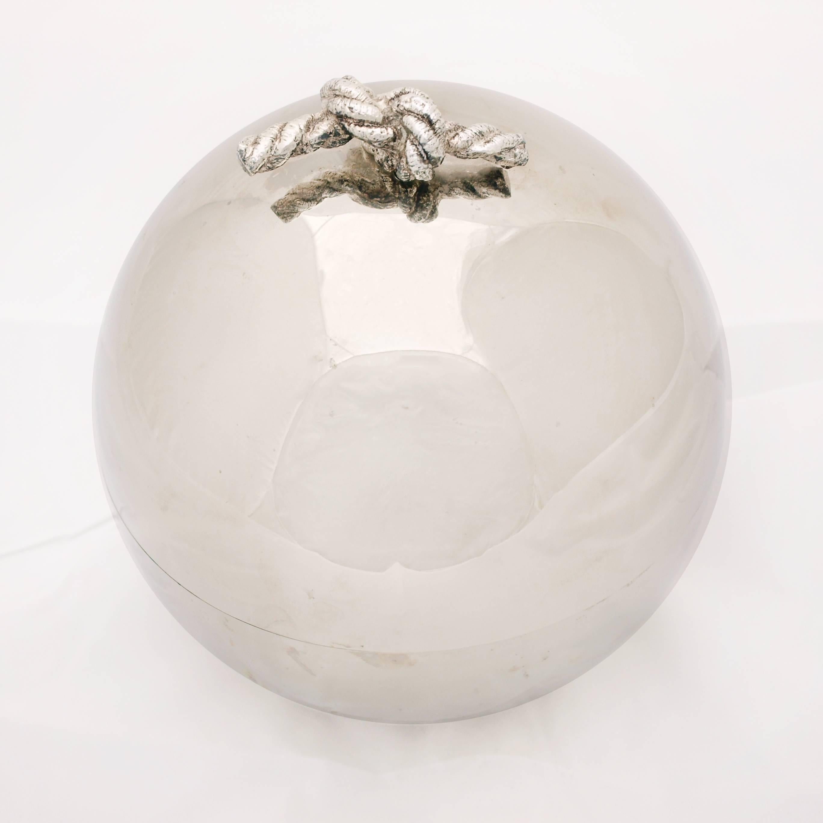 A 1970s spherical chrome effect ice bucket by The Turnwald collection. The lid of the ice bucket features a silver plated handle in the form of a knotted piece of rope. The lid meets the body neatly at the horizontal circumference. This is a