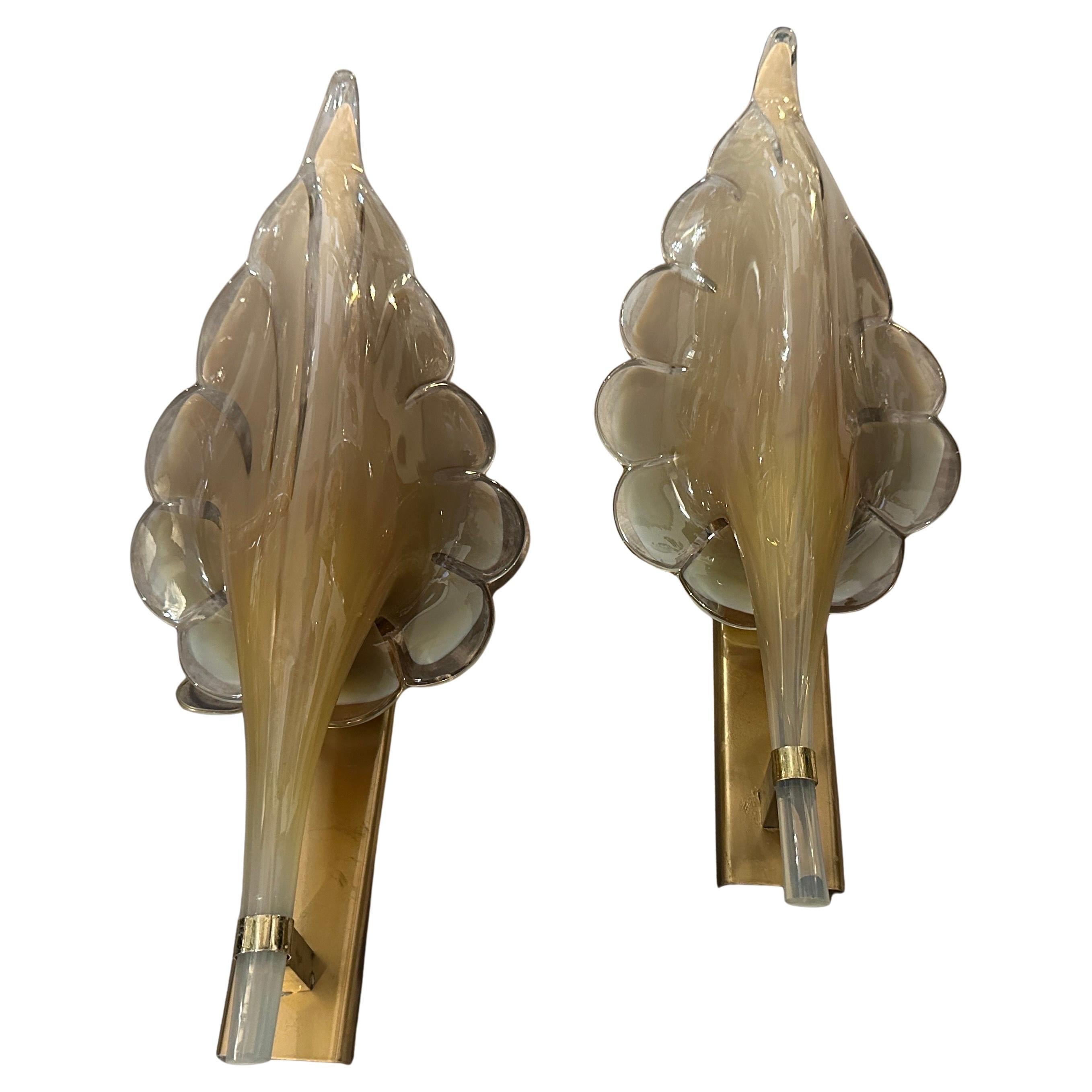 These are 1970s Mid-Century Modern wall sconces designed by Franco Luce. The sconces feature a striking leaf-shaped design made of hand-blown clear and walnut brown Murano glass, with a translucent finish and soft curves that create a warm inviting