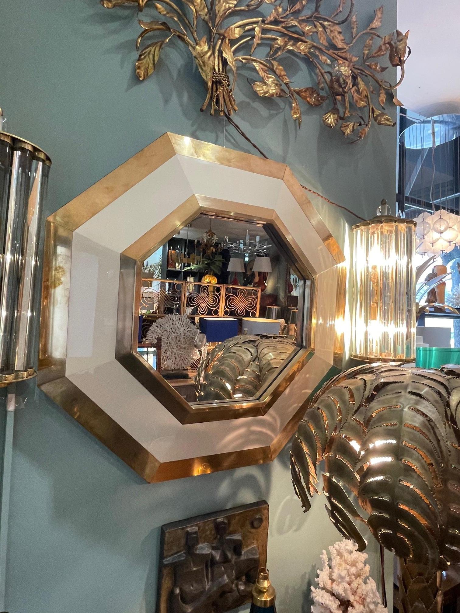 A lovely 1970s octagonal brass and ivory lacquer mirror by Jean Claude Mahey.