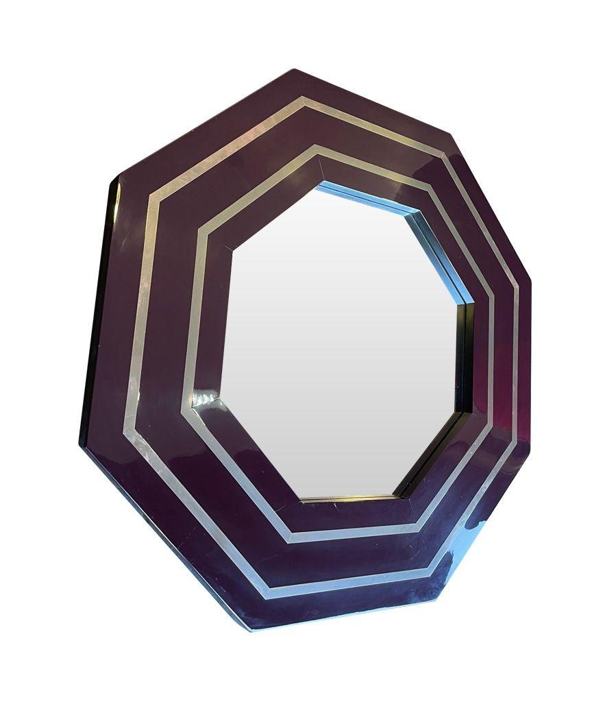 A 1970s octagonal mirror by Jean Claude Mahey with brass inlay frame finished in a deep brown, burgundy coloured lacquer.