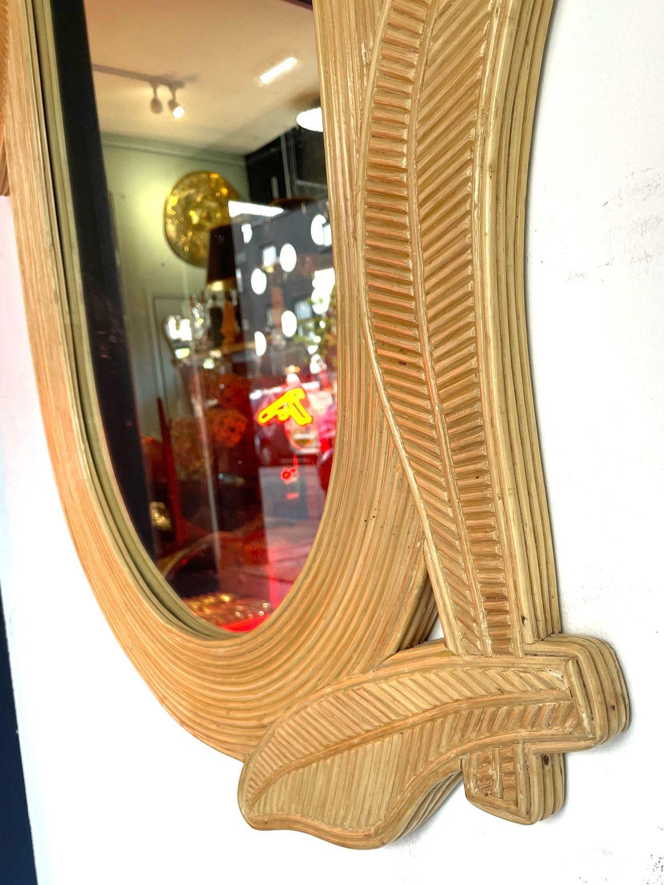 A 1970s oval shaped pencil reed bamboo mirror by Vivai del Sud with opposing corner leaf detail.