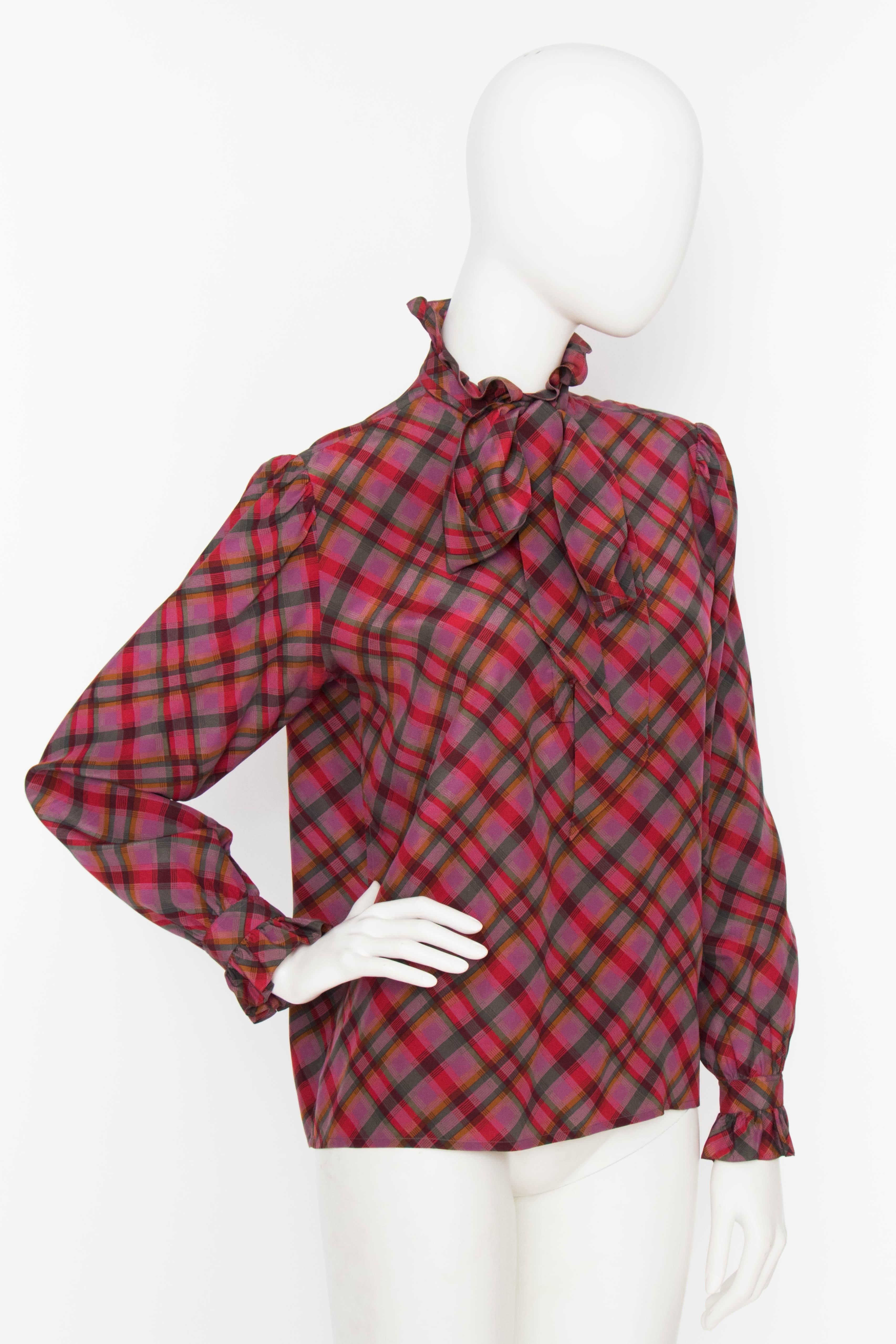 A 1970s Yves Saint Laurent Rive Gauche tartan silk blouse with a ruffle collar and ruffle trimmed cuffs. The shoulders are slightly puffed and a ribbon is attached to the collar. 

The size of the blouse corresponds to a modern size Extra Small.