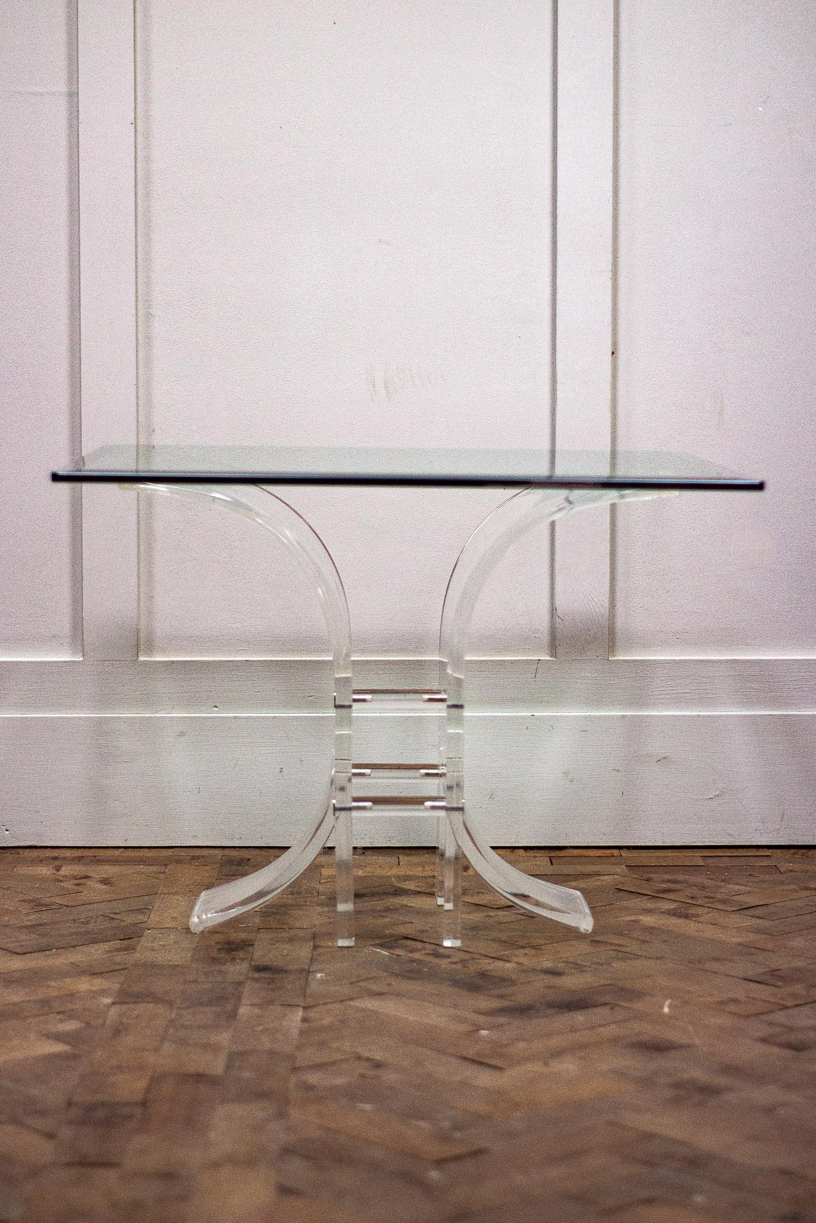 A clear Lucite and glass side table, 1980s. 

The base is constructed of two halves with three Lucite cylinders which fasten in between the two sides to form the table base. 

The glass top then simply sits on the base. 

Measures: Height-
