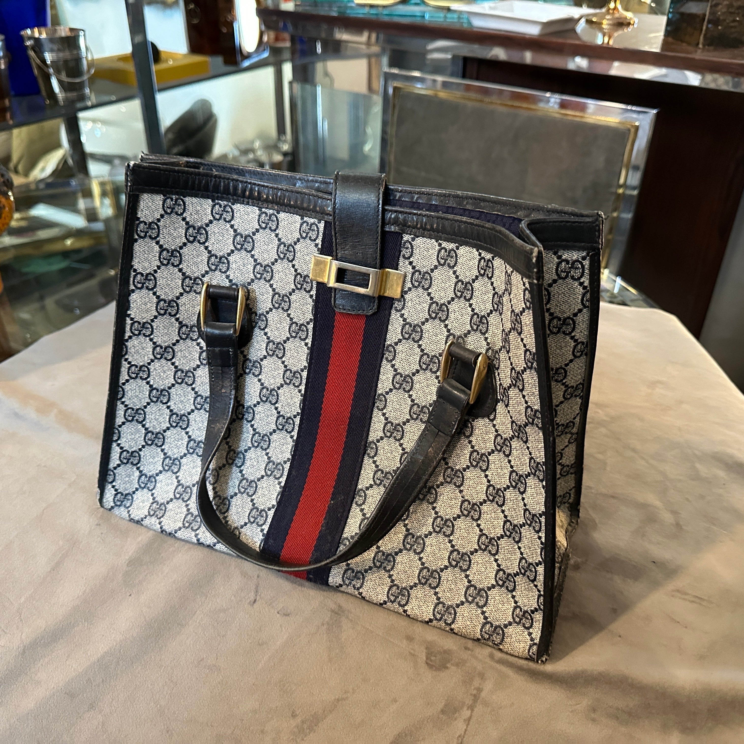 A 1980s iconic handbag by Gucci, characterized by the brand's signature motifs and timeless design. 
The bag features Gucci's classic GG monogram canvas, a signature pattern that embodies the luxury and heritage of the brand. The monogram is printed