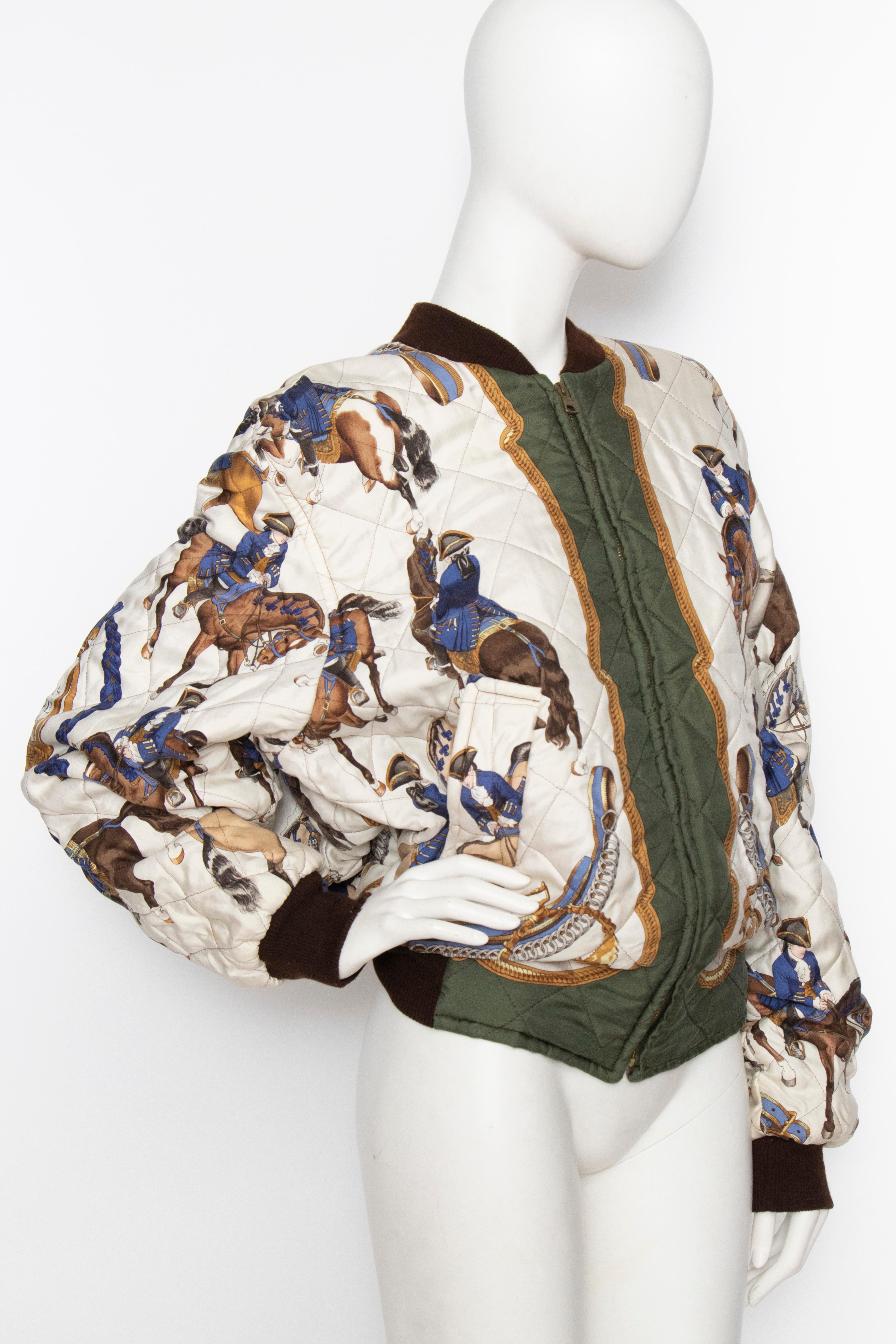 A 1980s reversible Hermès silk bomber jacket with a hunter green lining on one side and a white quilted on the other. The quilted side features a 'Reprise' motif. A brown elasticated cotton trim wrap around the collar and hemline. 

The size of the