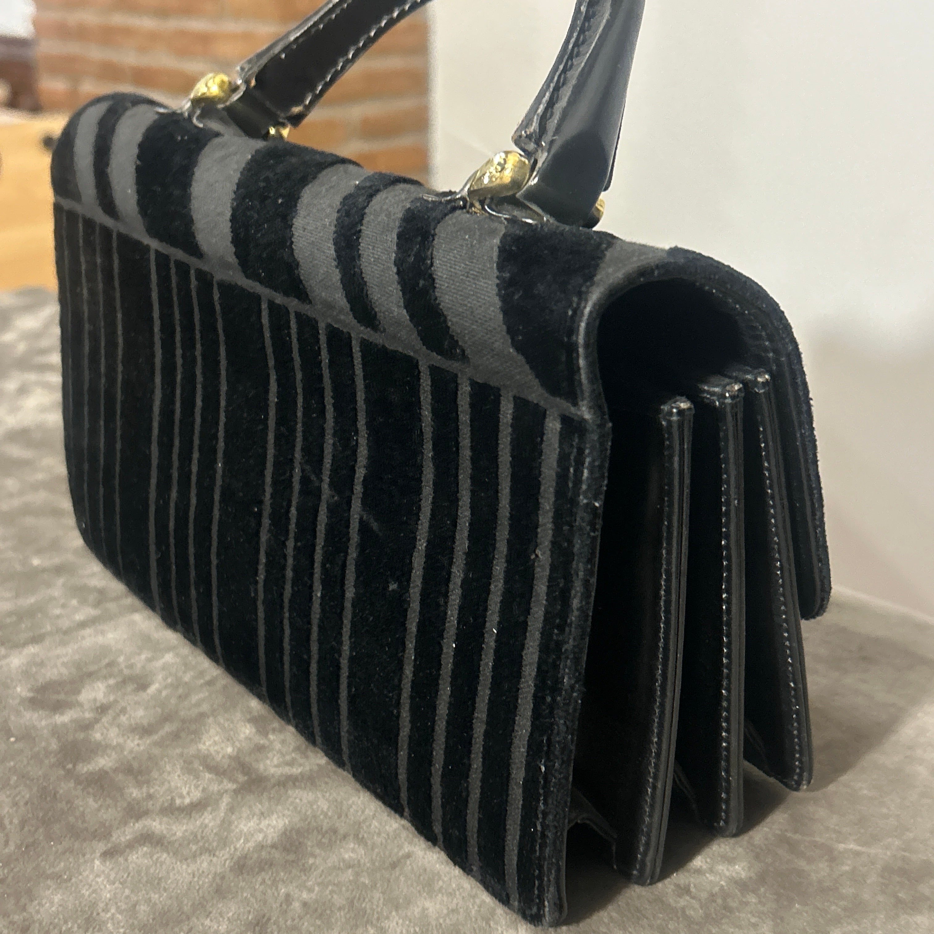 This 1980s vintage Italian evening bag by Roberta di Camerino is a refined and elegant accessory that perfectly captures the designer's signature style and craftsmanship. The bag combines rich textures and classic design elements, making it a