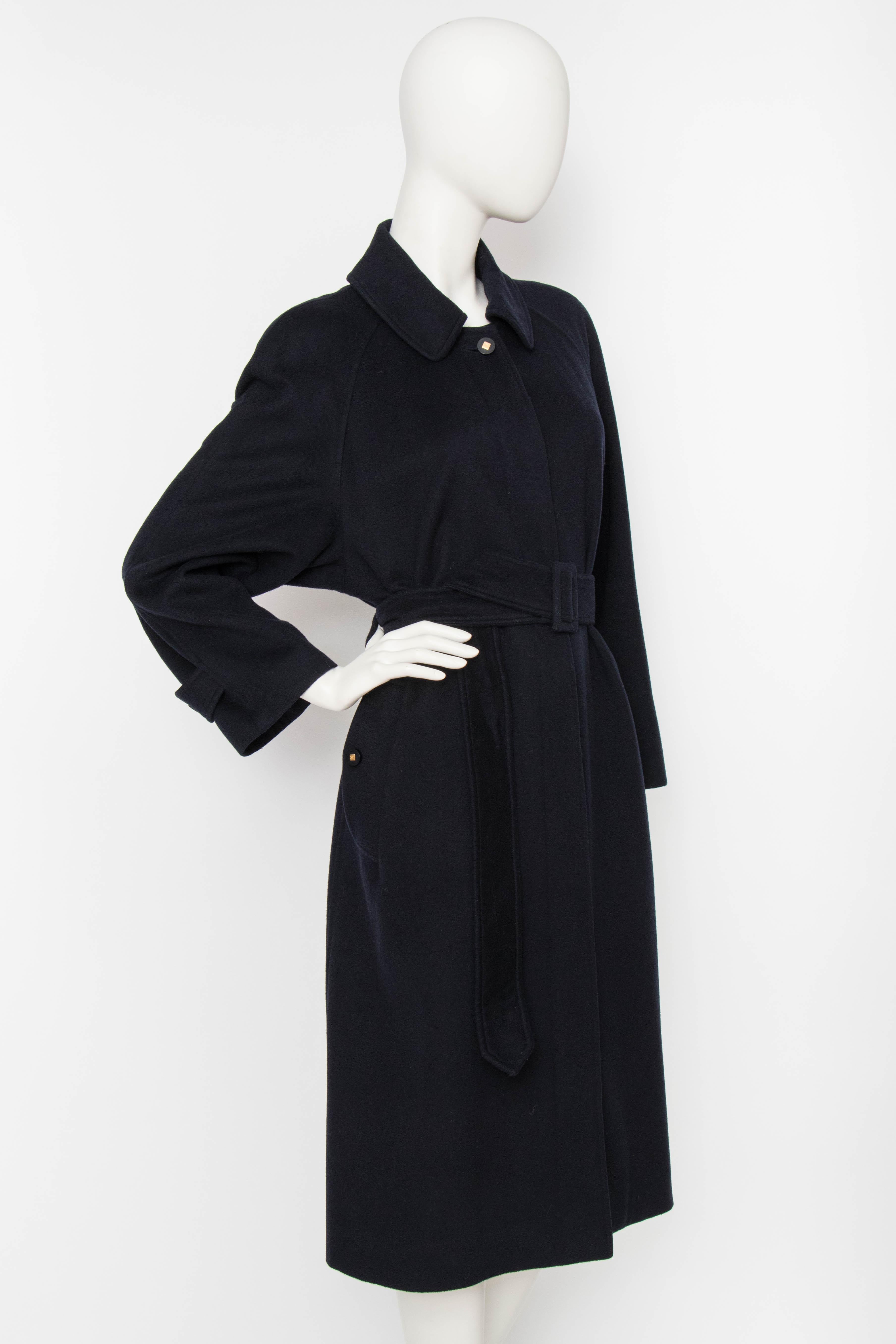 An incredible 1980s navy cashmere Chanel coat with a hidden front button closure, raglan sleeves and matching waistbelt. The coat is lined in navy silk. The top button and the buttons at the adjustable cuff is navy with a gold-toned center which is