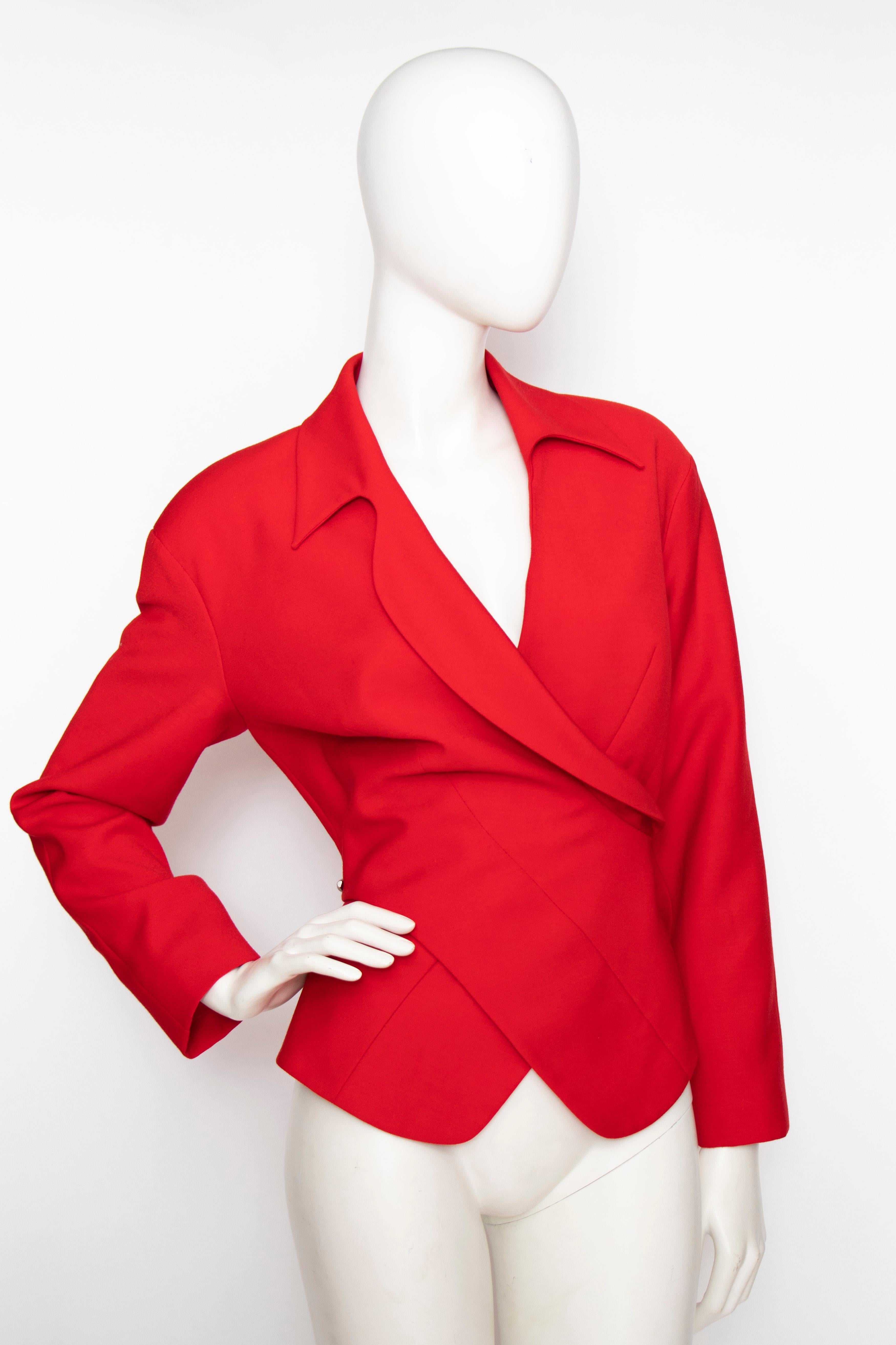A 1980s vintage Thierry Mugler bright red wool blazer with a fitted waist and iconic exaggerated shoulders. The stunning blazer has a wrap closure, rounded lapels and is held together by chrome toned 