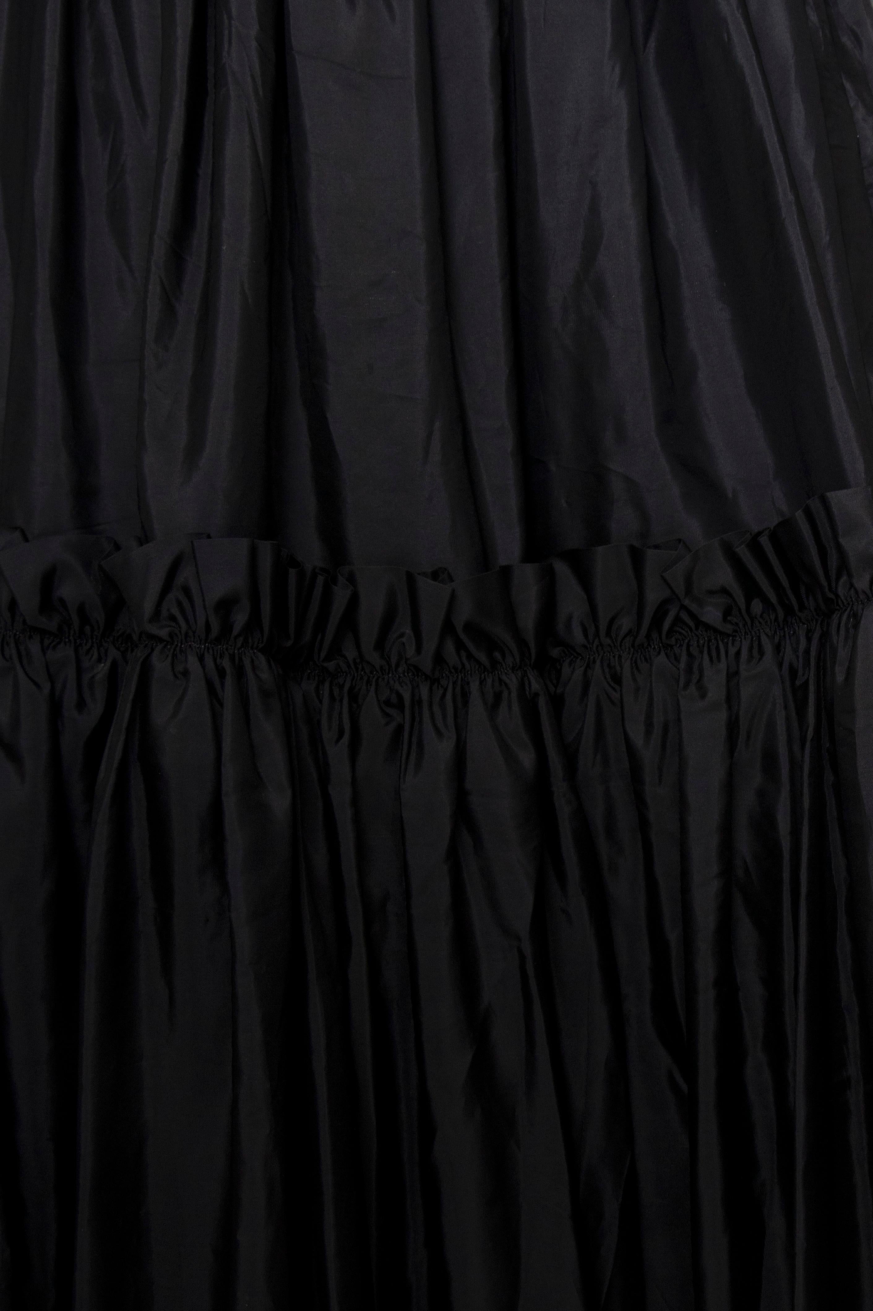 A 1980s Vintage Yves Saint Laurent Rive Gauche floor-length black silk taffeta skirt with a fitted waist, zipper closure and gorgeous ruffled trimmed layers. The skirt is unlined. 

The size of the skirt corresponds to a modern size Small, but