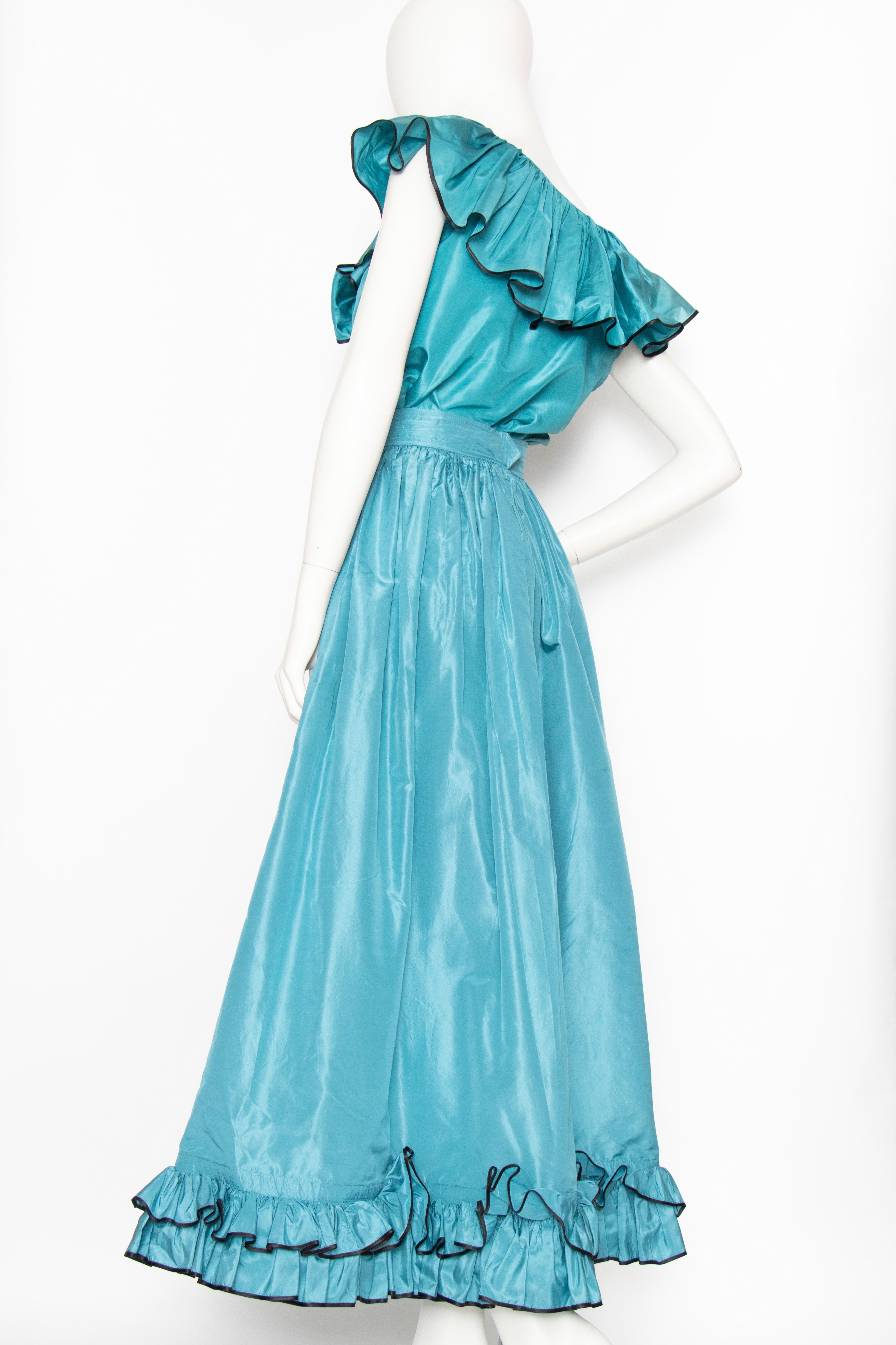 An incredible 1980s Yves Saint Laurent luscious teal blue silk taffeta two-piece dress consisting of a wide a-line skirt and sleeveless top. Both items have a ruffle detail, the skirt at the hem and the blouse at the collar complete with bow detail.