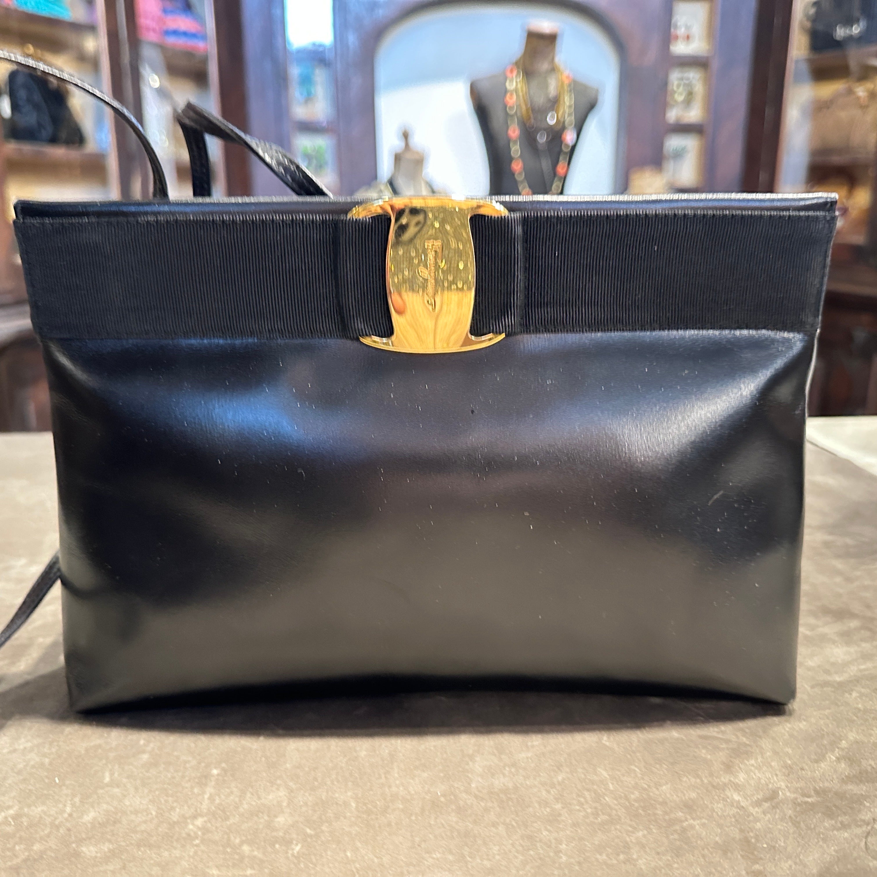 1990s Salvatore Ferragamo Black Leather and Brass Vara Shoulder Bag
A timeless classic from the esteemed Italian house of Salvatore Ferragamo, this elegant 1990s shoulder bag embodies sophisticated minimalism and enduring style. Crafted from