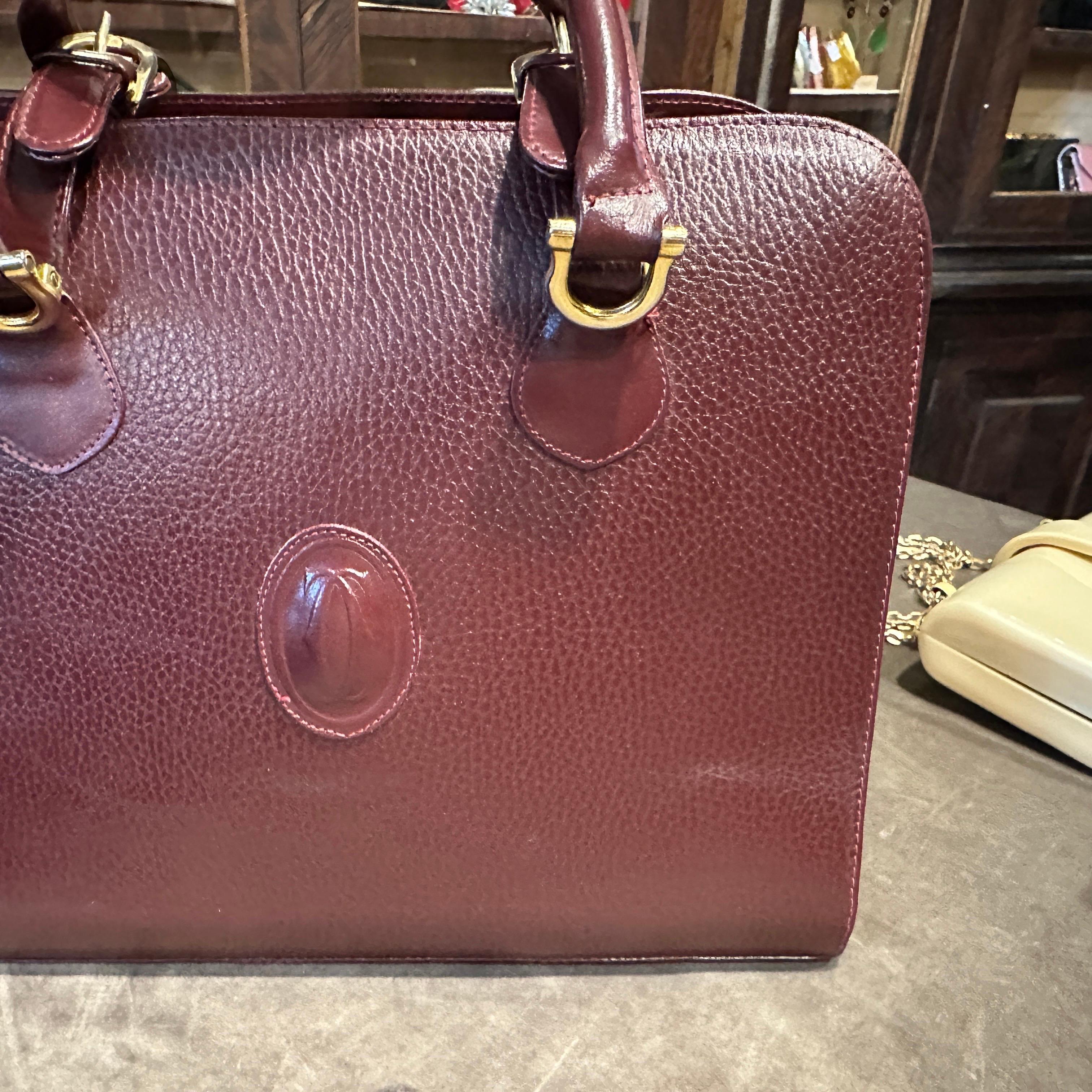 1990s Cartier Elegant Burgundy Leather and Gold-Tone Brass Top Handle Bag
Embrace timeless sophistication with this exquisite 1990s Les Must de Cartier top handle bag, a quintessential accessory embodying the luxury and refinement synonymous with