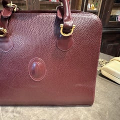 A 1990s Elegant Bordeaux Leather and Brass Top Handle Bag by Cartier