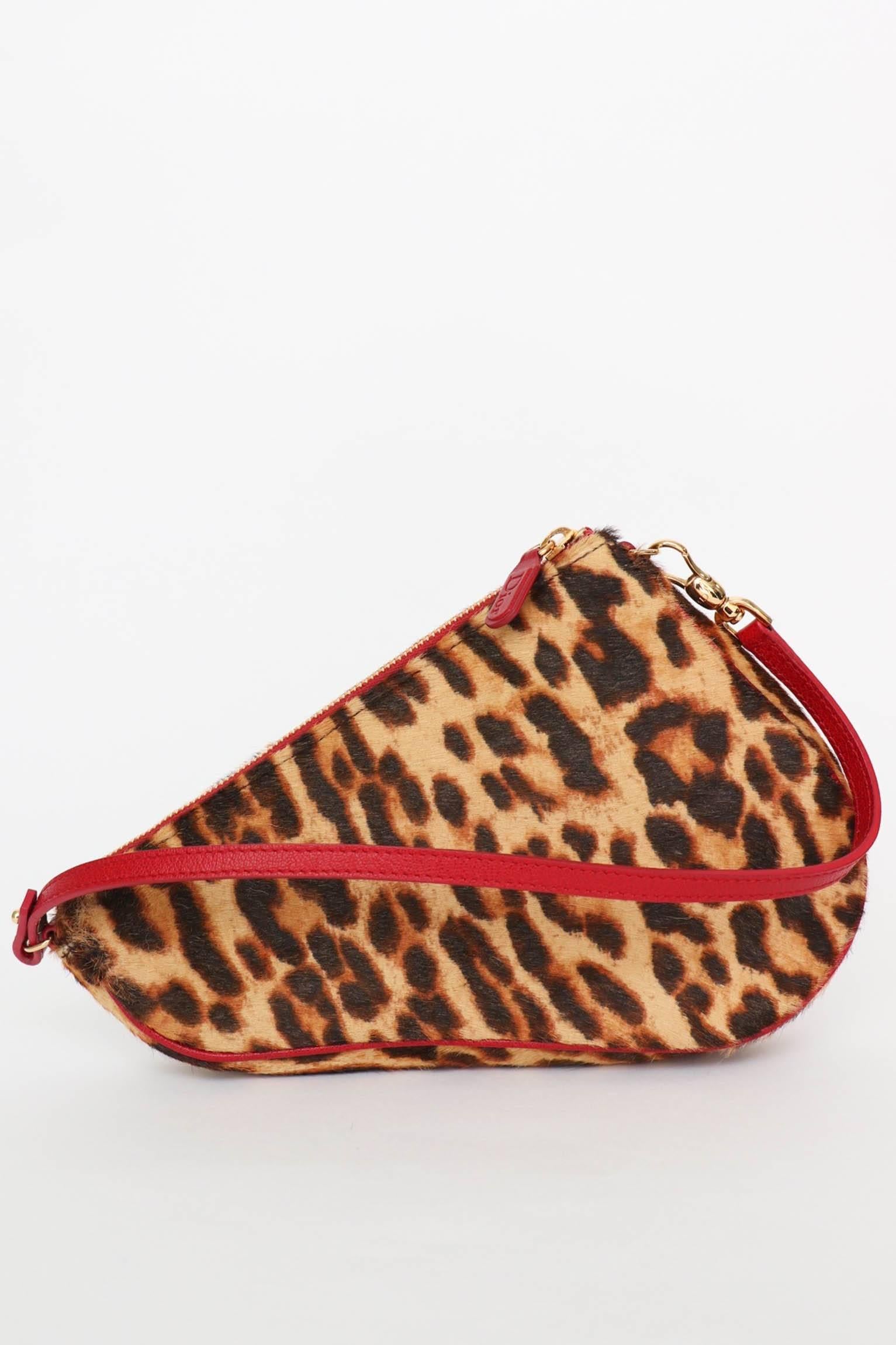 A fabulous 1990s Christian Dior animal printed pony hair saddle bag with a pink leather strap, gold hardware, and a small pink leather plate. 
The bag has a zipper closure, one large compartment and a small pocket with a zipper closure. The lining