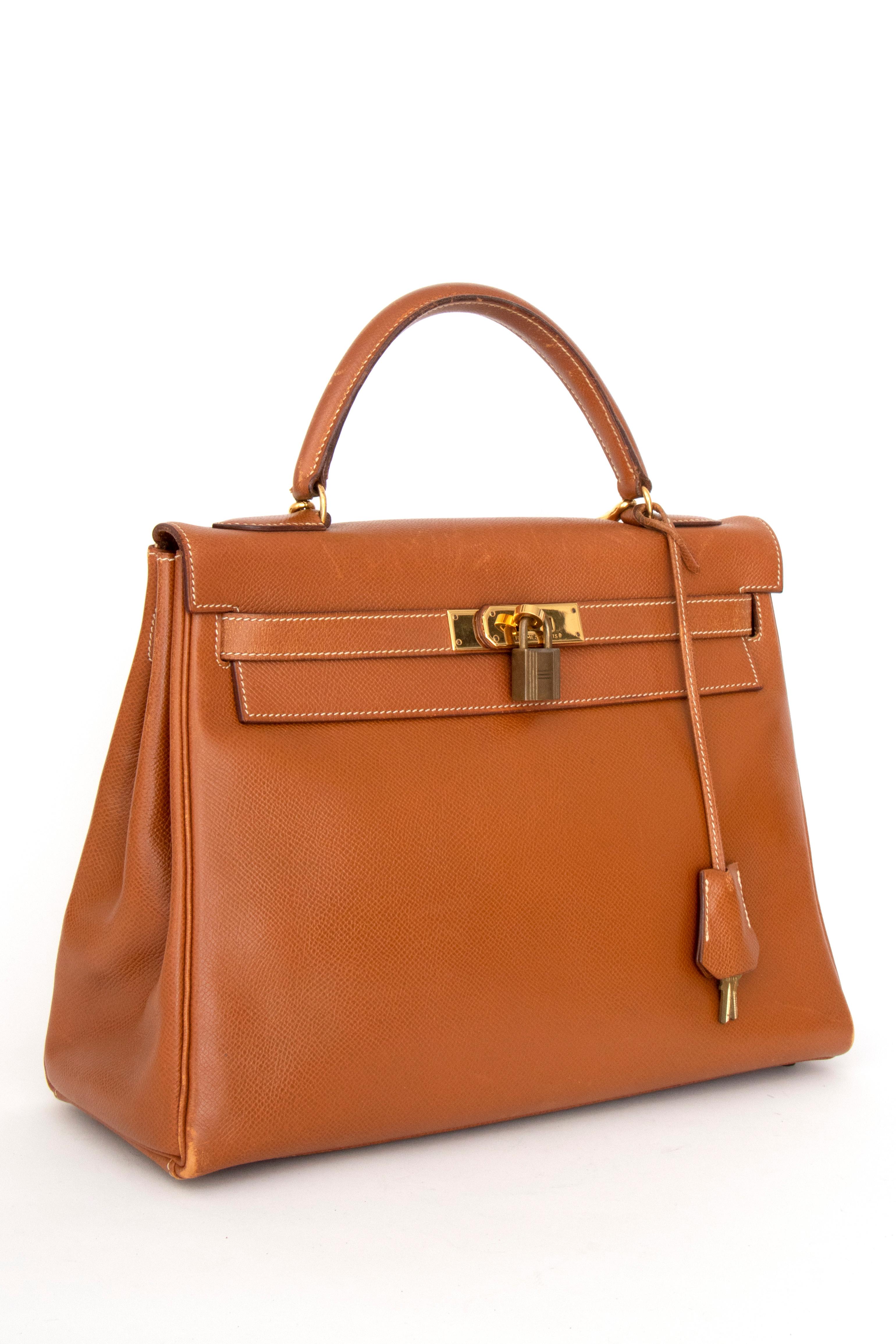 A 1990s vintage Hermès Kelly epsom handbag with gold hardware, a front toggle closure, lock and key, and a detachable strap for easier wear.

The bag has the following measurements:
Height: 23 cm
Width: 32 cm
Depth: 12 cm

This is a vintage bag