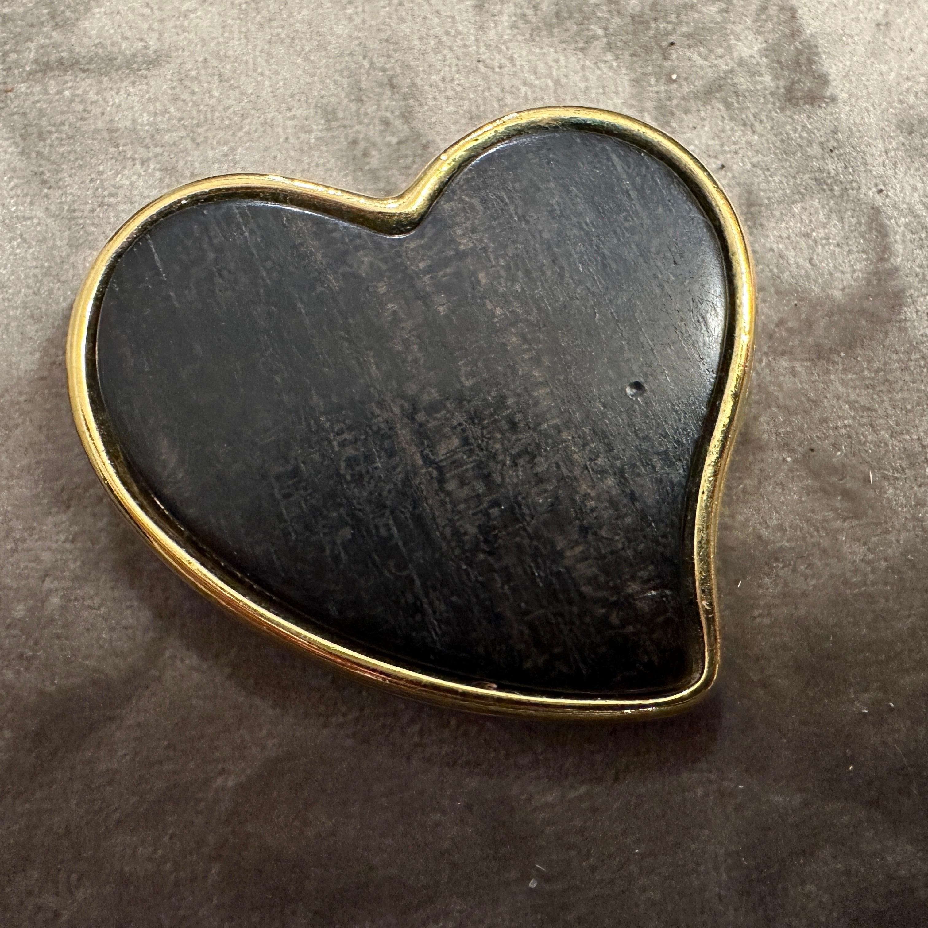 This is a vintage Yves Saint Laurent heart brooch from the 1990s, crafted with an elegant combination of wood and brass. The brooch features a smooth, dark wooden heart as its centerpiece, exuding a natural and sophisticated charm. The heart is