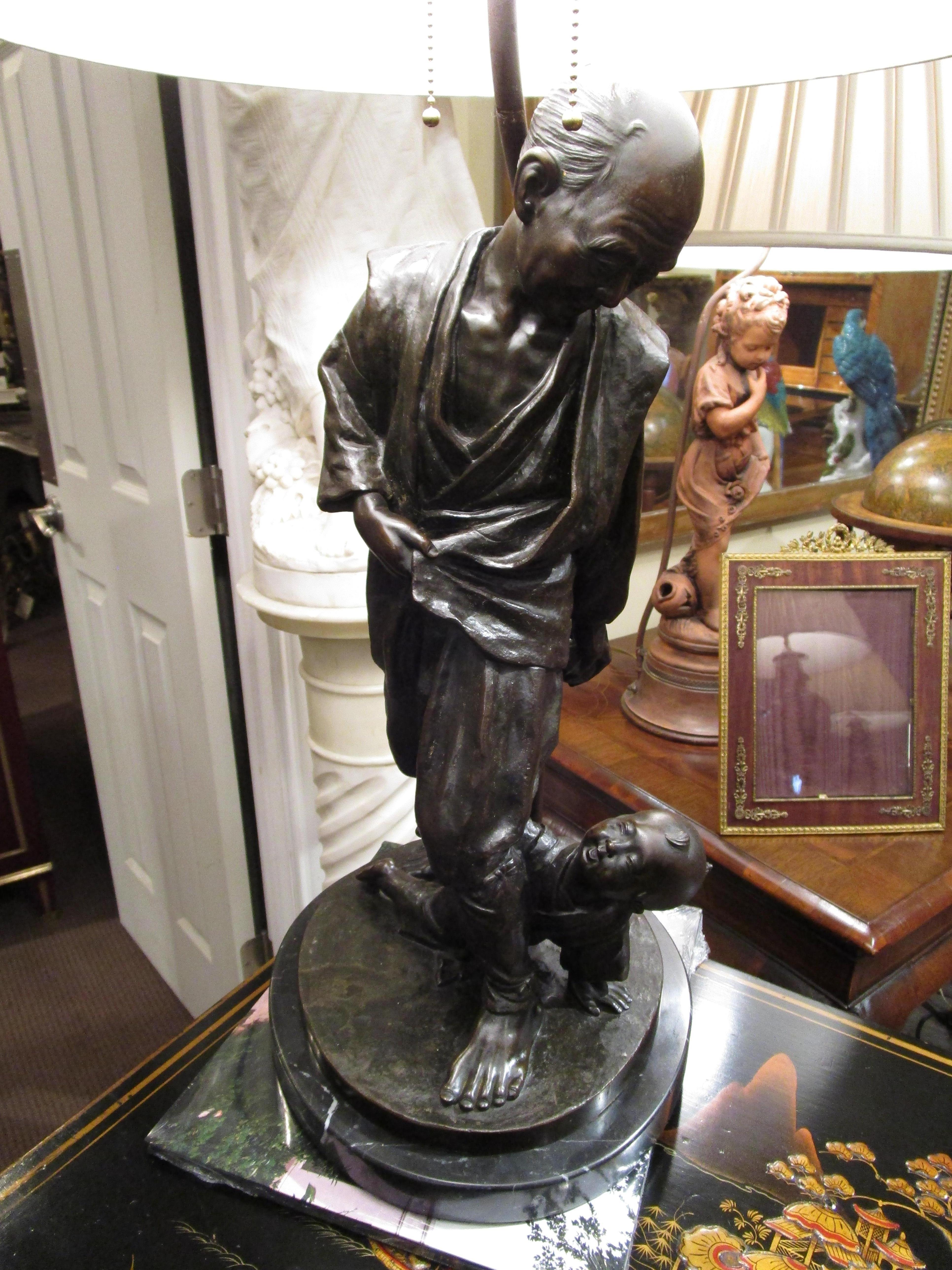 A large and fine 19th century patinated bronze sculpture of a man and his son. Custom made into a lamp with a marble base and a antique finial.