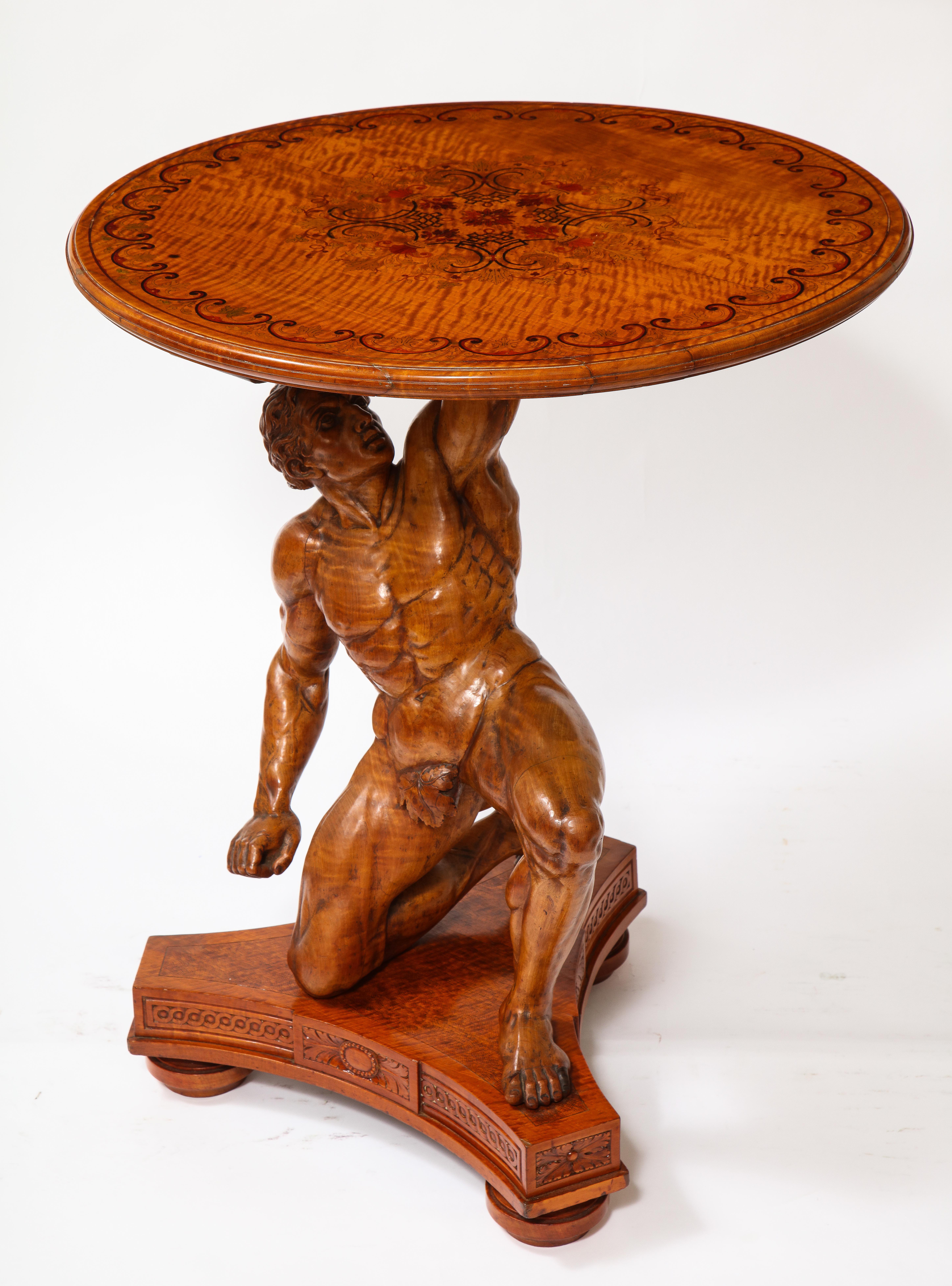 Une fabuleuse table d'atlas en bois sculpté à la main et en marqueterie du 19e siècle, signée J. Plucknett & Co. Warwick, Angleterre. La figure d'Atlas, magnifiquement sculptée à la main, est agenouillée sur une base triangulaire ornée de motifs en