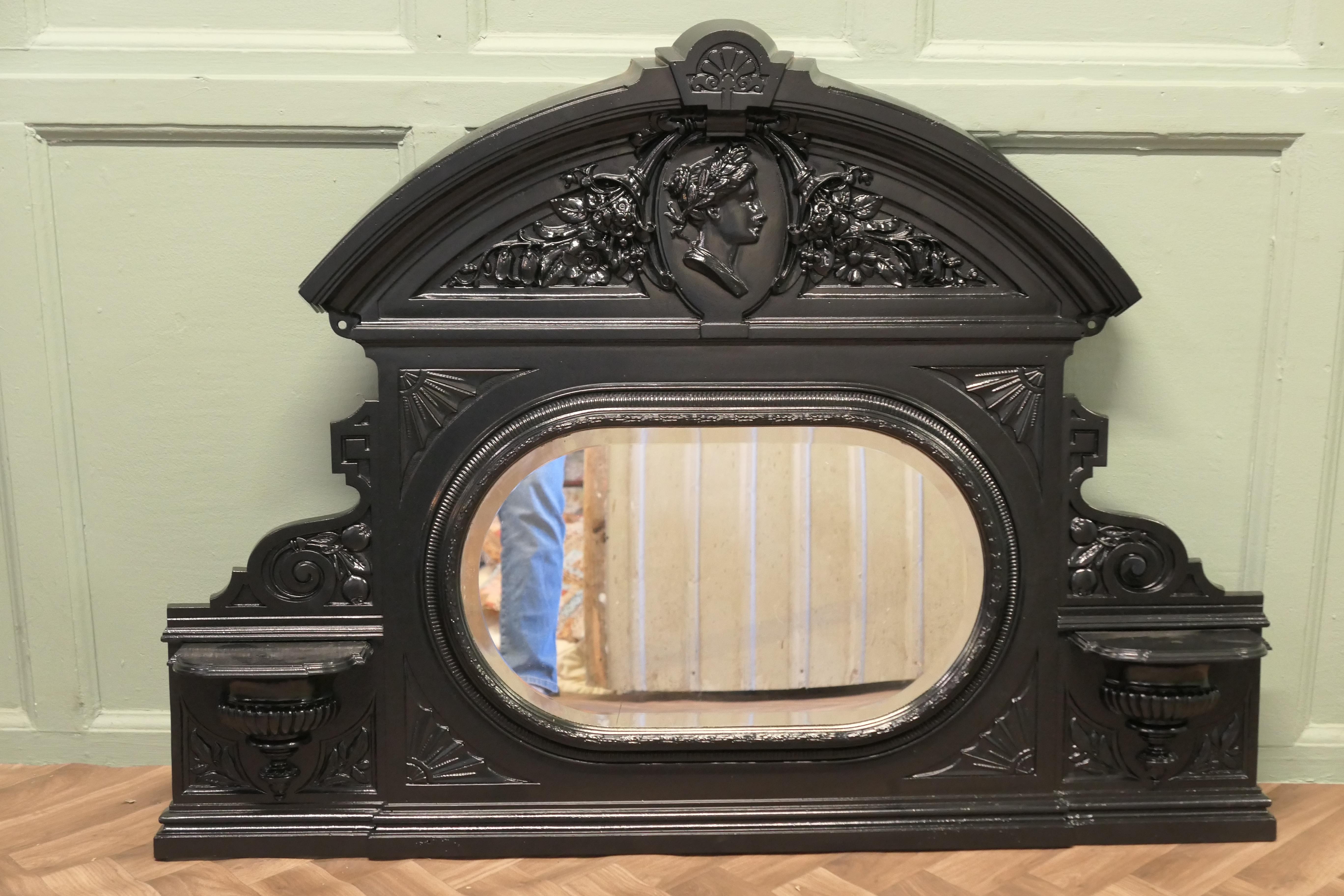 A.C.I.C., miroir à trumeau en fonte.
Il s'agit d'un lourd miroir de cheminée, qui aurait été placé au-dessus d'une cheminée en fonte et vissé au mur. Il est de style Empire français, avec son verre biseauté d'origine et décoré d'une représentation