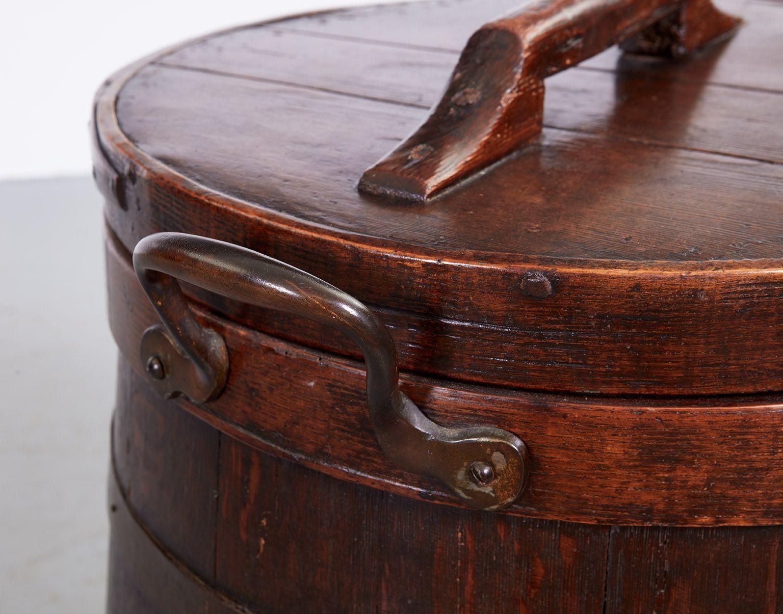 A 19th century oak bin for the storage of hardtack, a type of dense and long-lasting biscuit, on long clipper ship voyages.  The bin is of staved construction, with willow and iron banding, and has a lid with a shaped handle.  It is wider at the