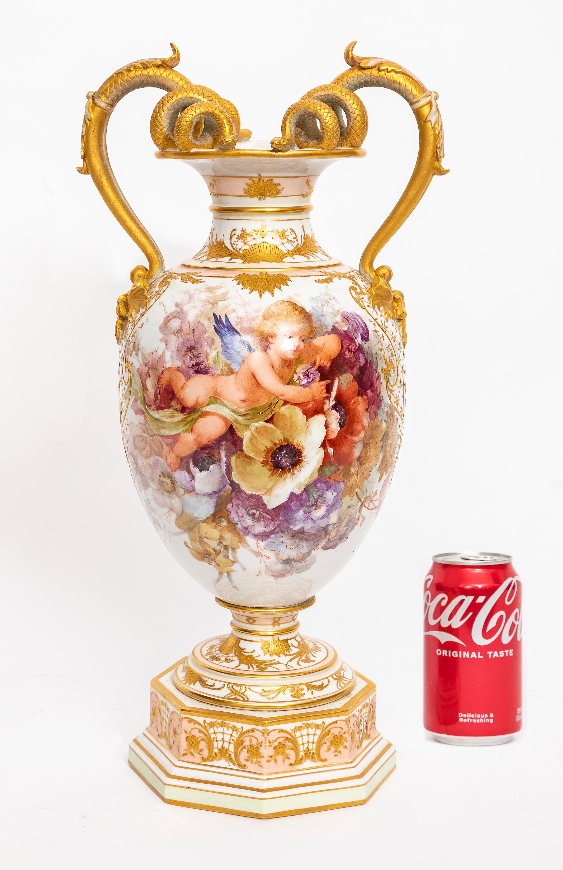 A Marvelous 19th Century KPM Porcelain Weichmalerei Flower Decorated Double Snake Handle Vase with Butterfly Decoration and Putti.  The vase features an amphora form with an octagonal stepped base adorned with raised 24k gold decorations that are