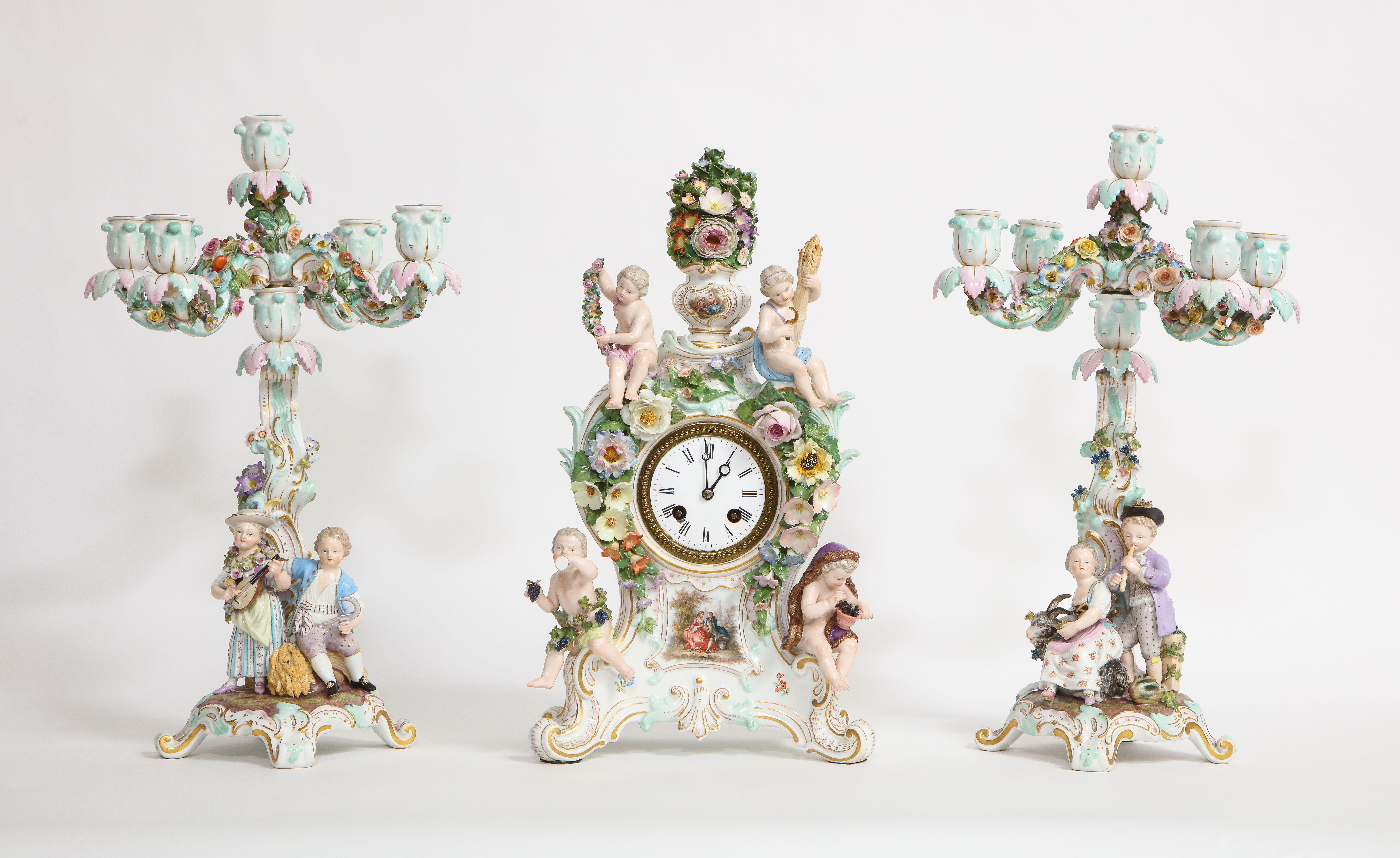 Eine beeindruckende und seltene Meissener Porzellan Vier-Jahreszeiten-Uhr und Kandelaber Garnitur des 19. Jahrhunderts. Bestehend aus drei Einzelteilen, darunter eine wunderschöne Uhr und zwei passende Kandelaber. Die Uhr besticht durch die