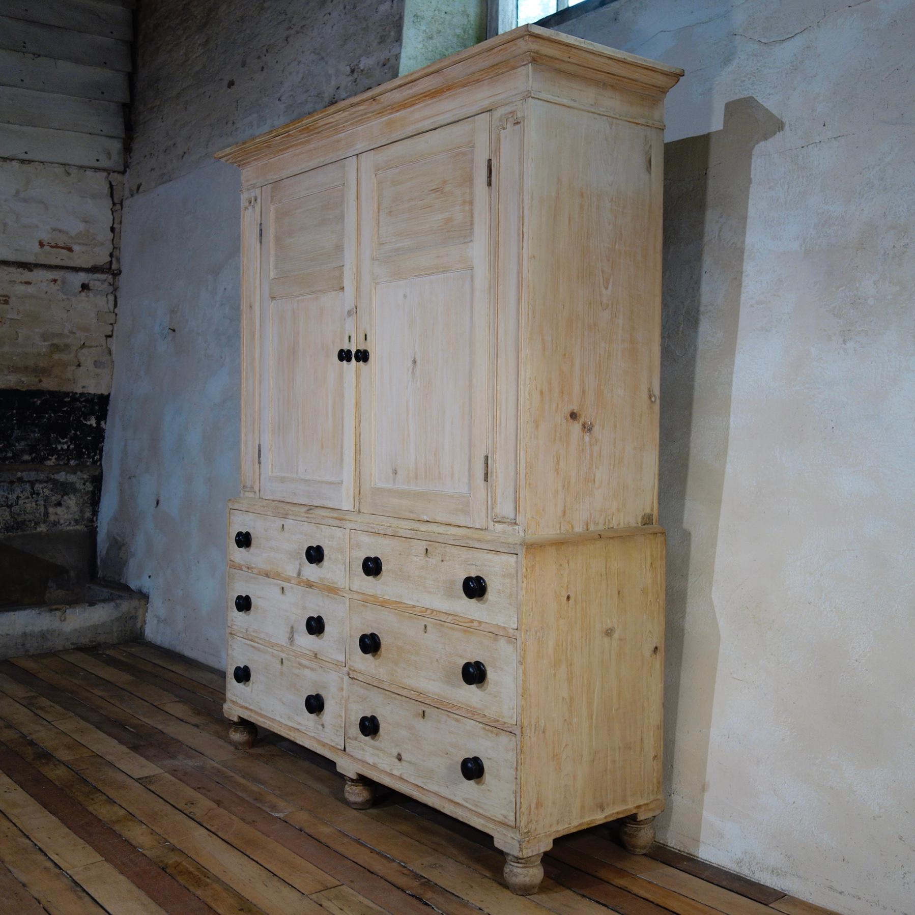 A superb 19th century bleached Pine House Keepers cupboard. Displaying six drawers with turned ebonised handles. The top demonstrating panel doors with the interior painted in a white, cream tone.

Measures: Height 202cm
Width 160cm 
Depth 53cm.